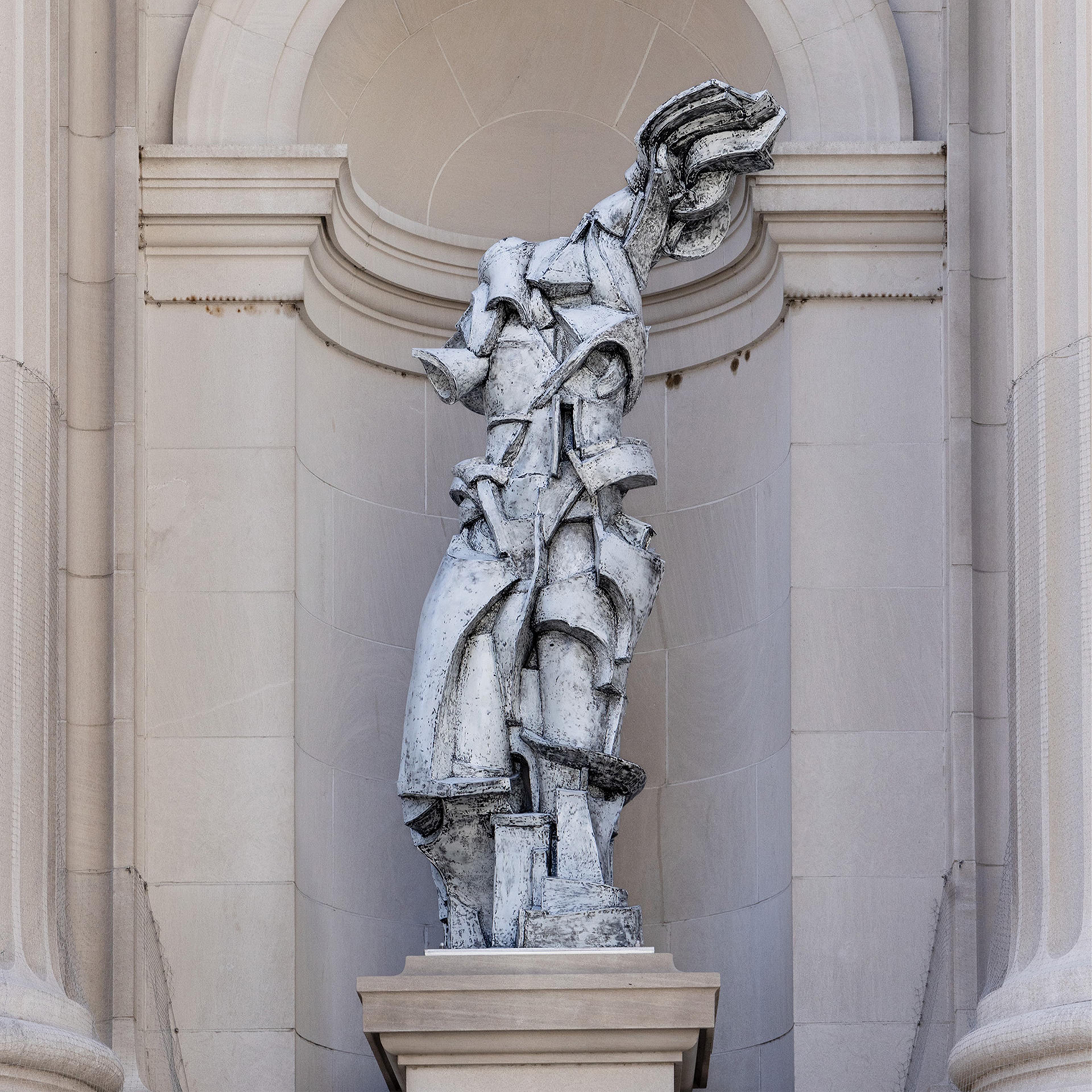 Futuristic sculpture of a fragmented, abstract human form in stone against a neoclassical arch. The tone is dynamic and modern amidst classical architecture.