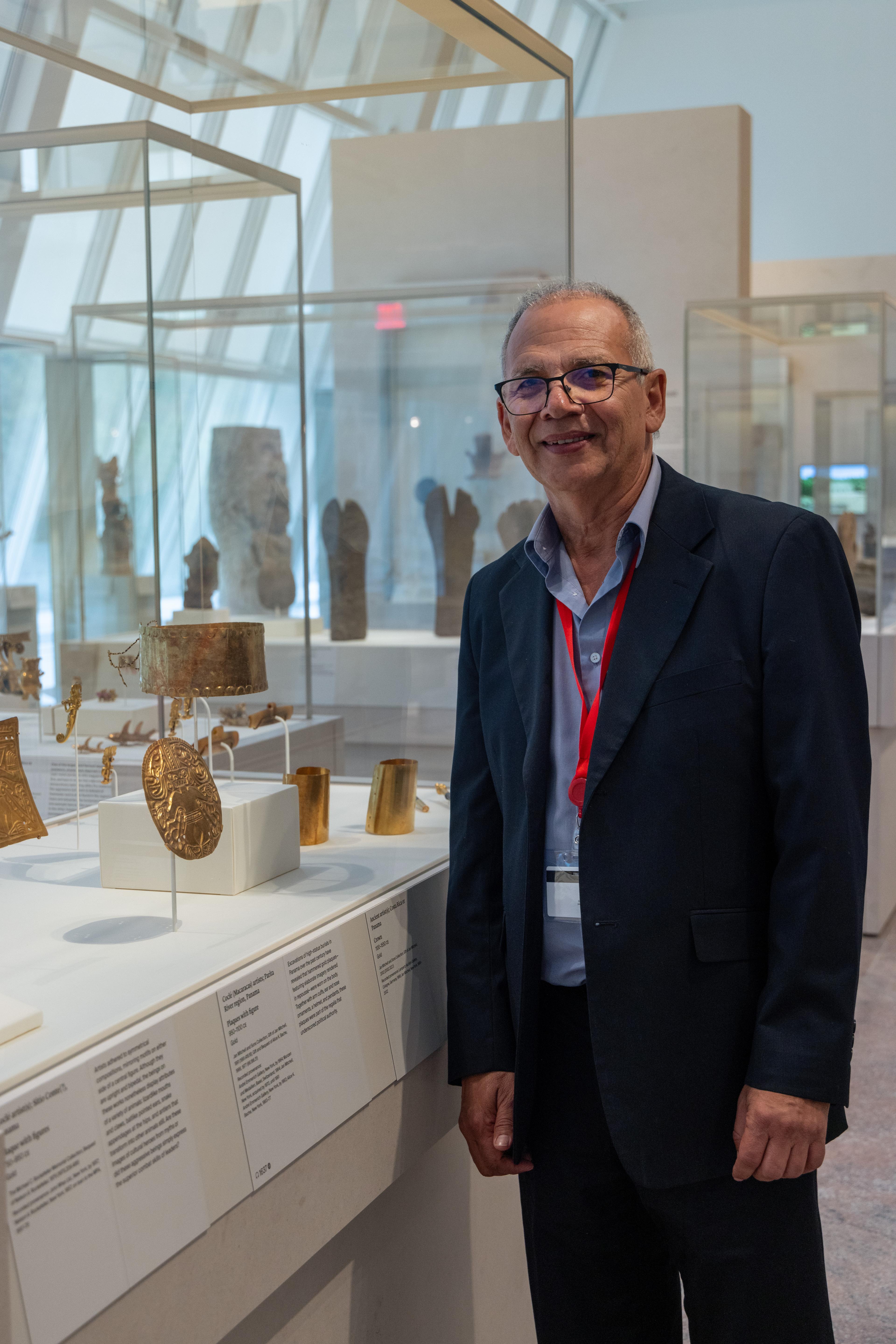 Francisco Corrales Ulloa posing with a gold plaque in the Arts of the Ancient Americas galleries