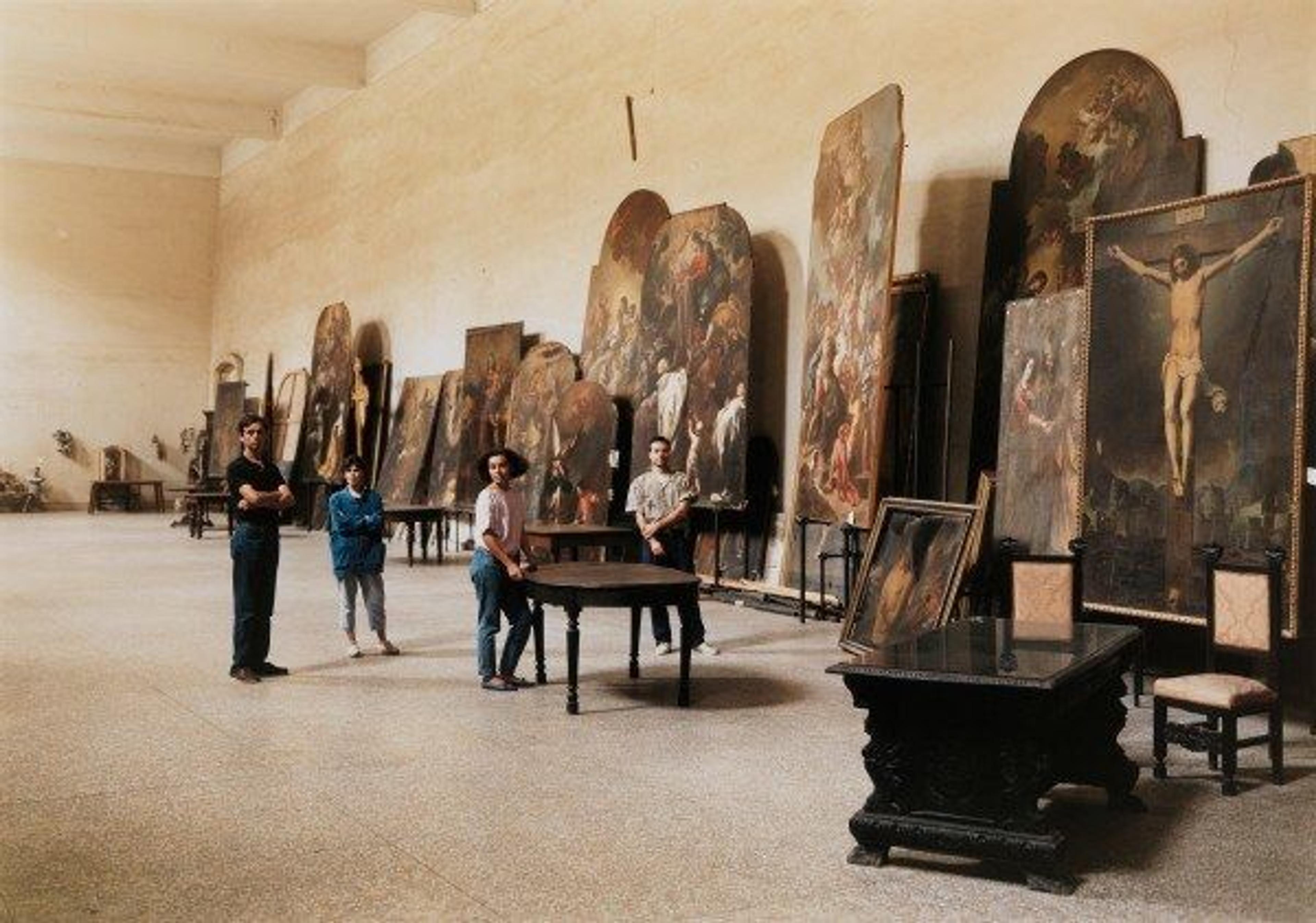 A large-scale color photograph by Thomas Struth of four art restorers posing in a large room full of religious artworks