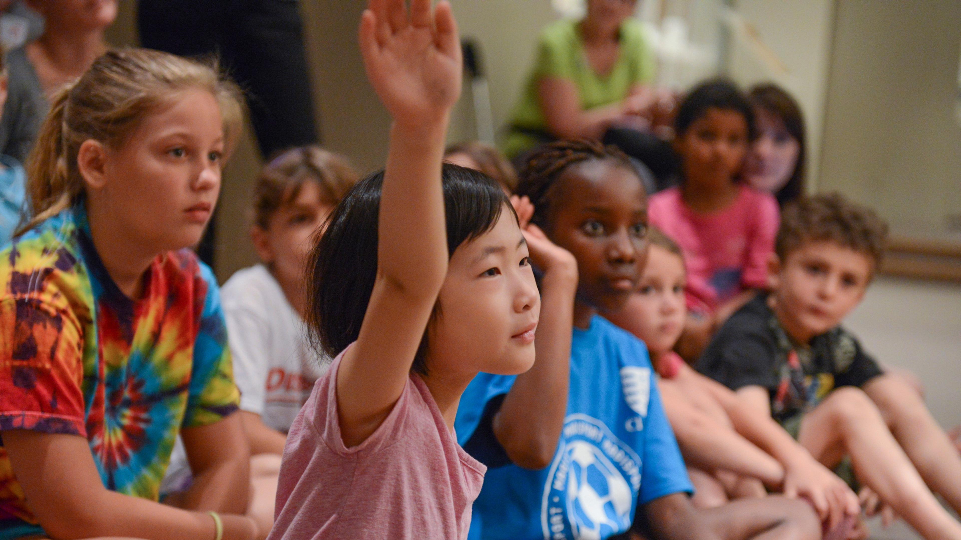 Young children raising their hands.