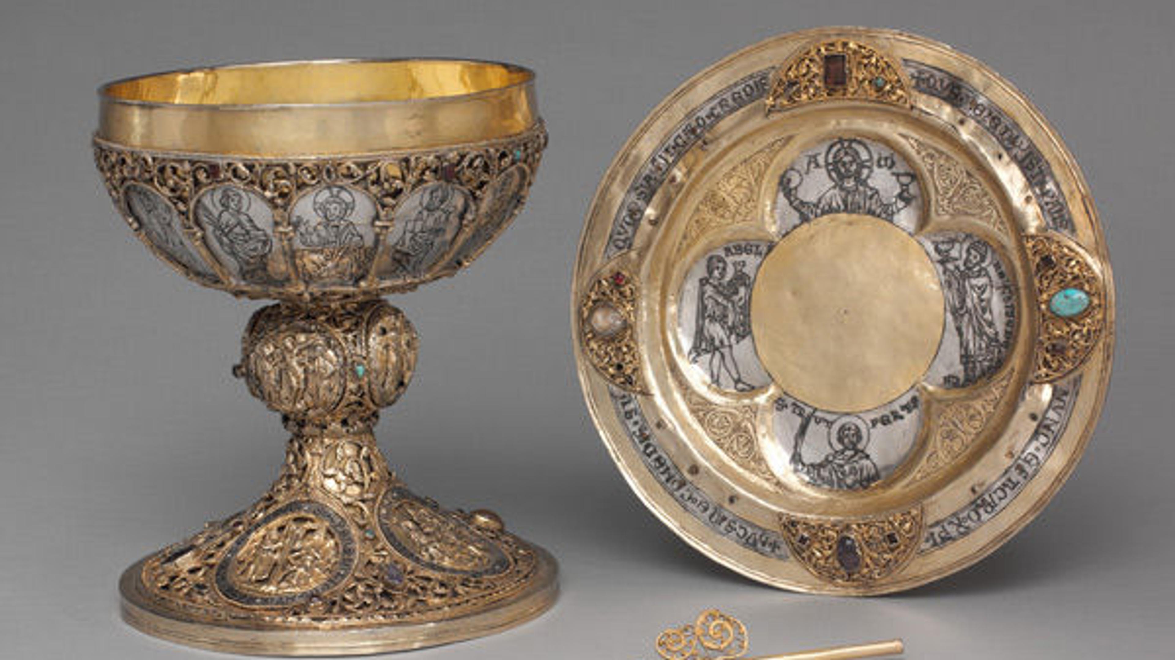 Chalice, plate, and straw ornately made of gold with religious imagery.