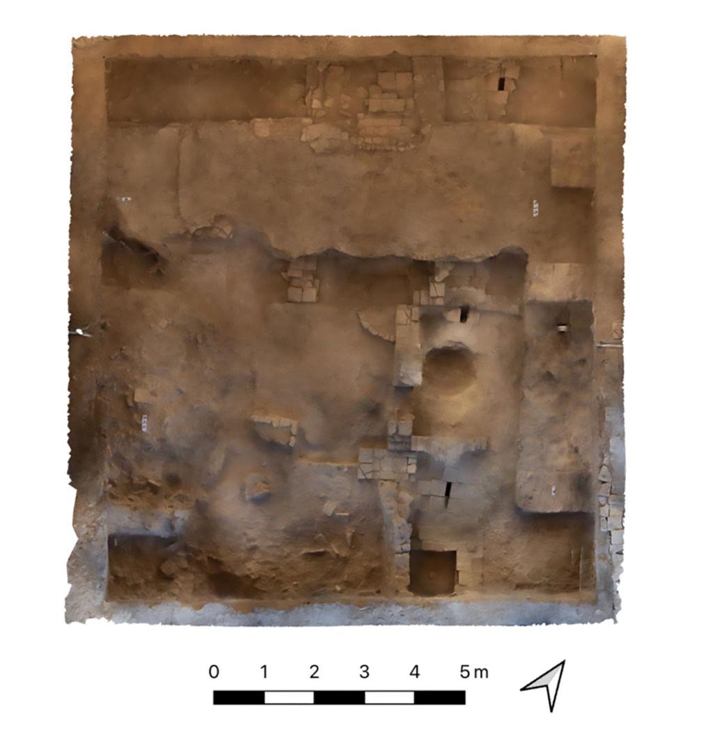 Photogrammetry scan of excavated area at Dandanakan. The scan shows a series of rooms with pits. A north arrow and scale bar orient the viewer.