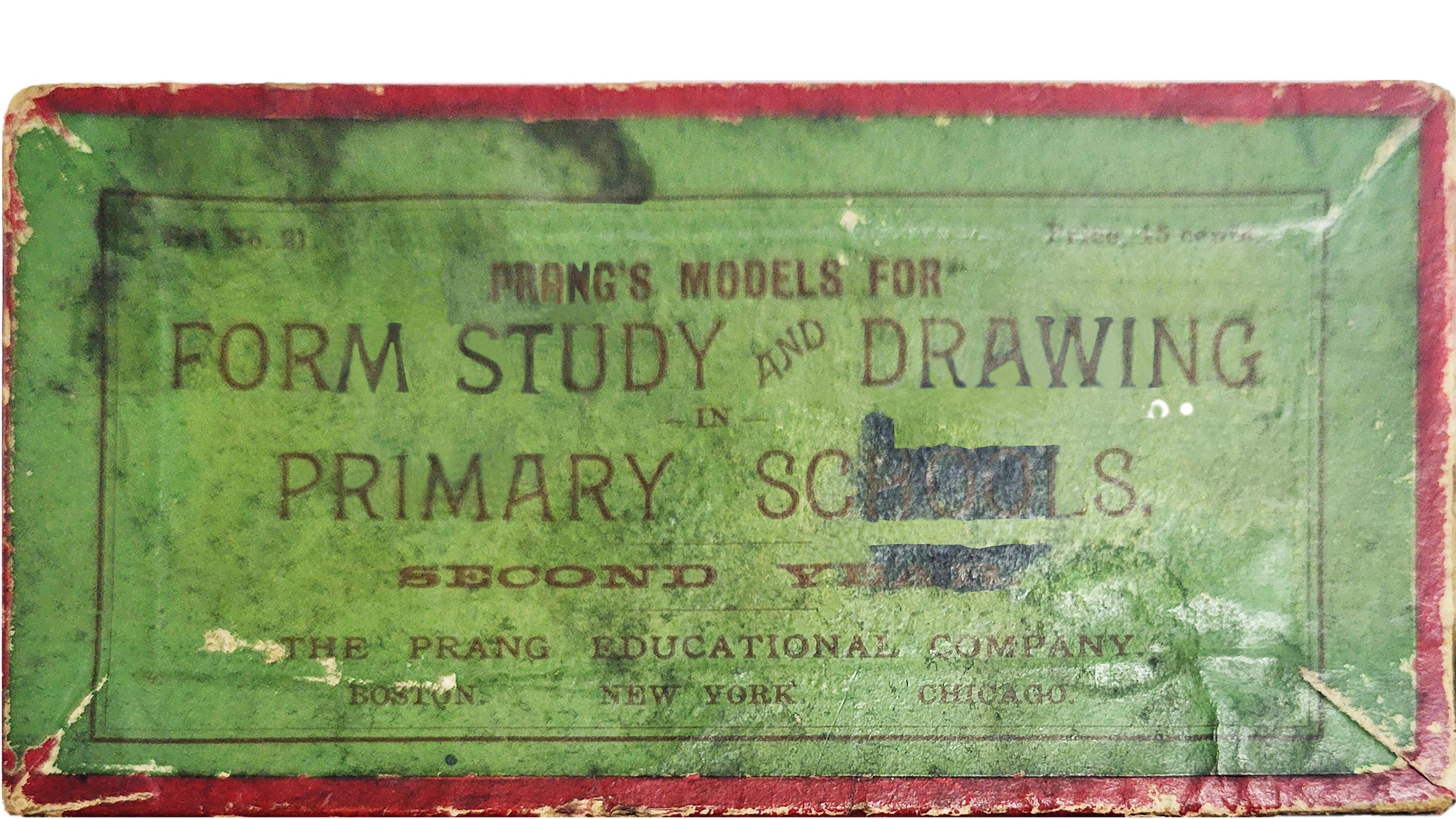 Close-up of a worn green box cover with faded lettering reading “Prang’s Models for Form Study and Drawing in Primary Schools.”