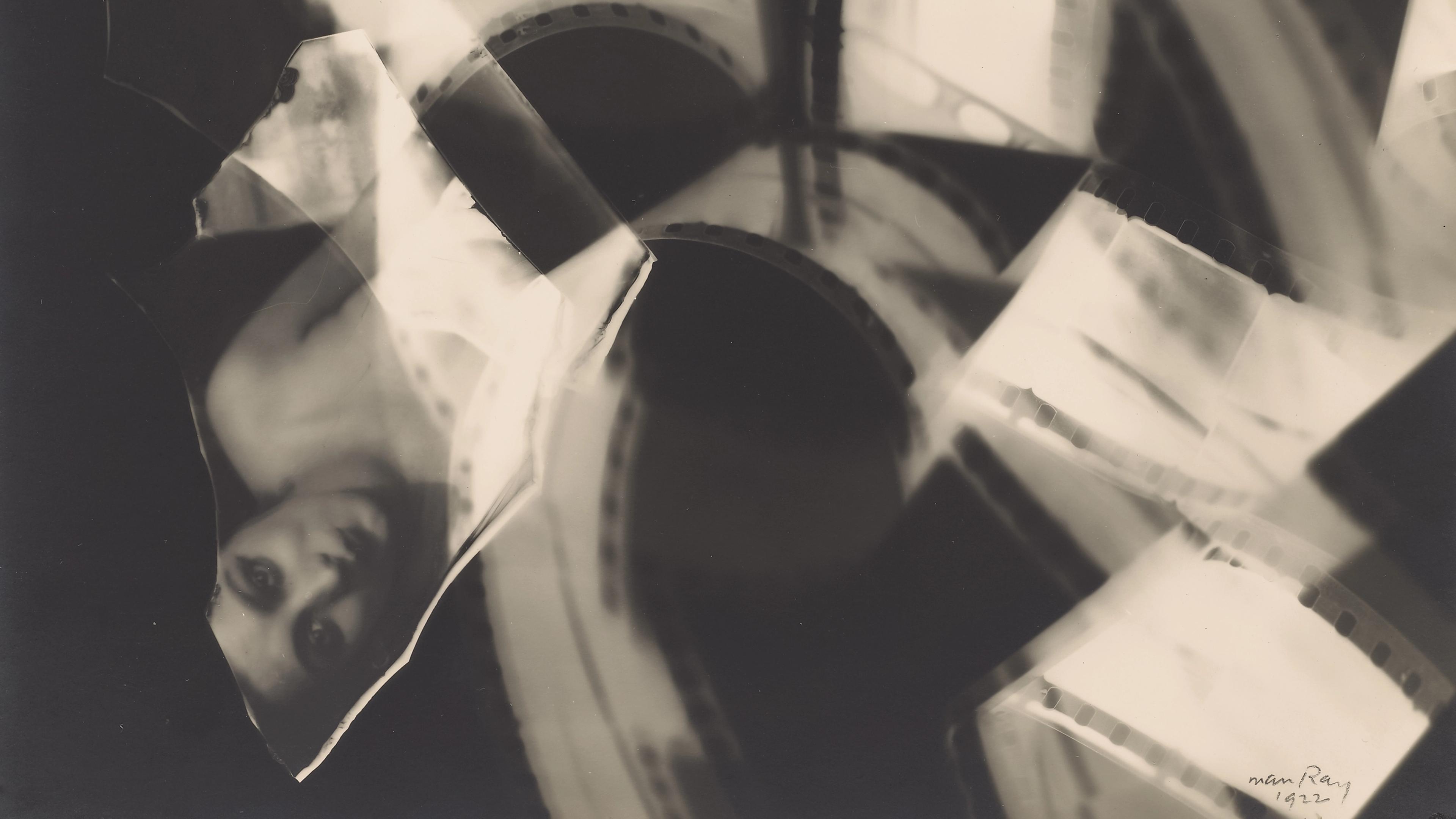 Black-and-white photogram featuring overlapping strips of photographic film, curved bands of sprocket holes, and a partially visible upside-down face against a dark background.