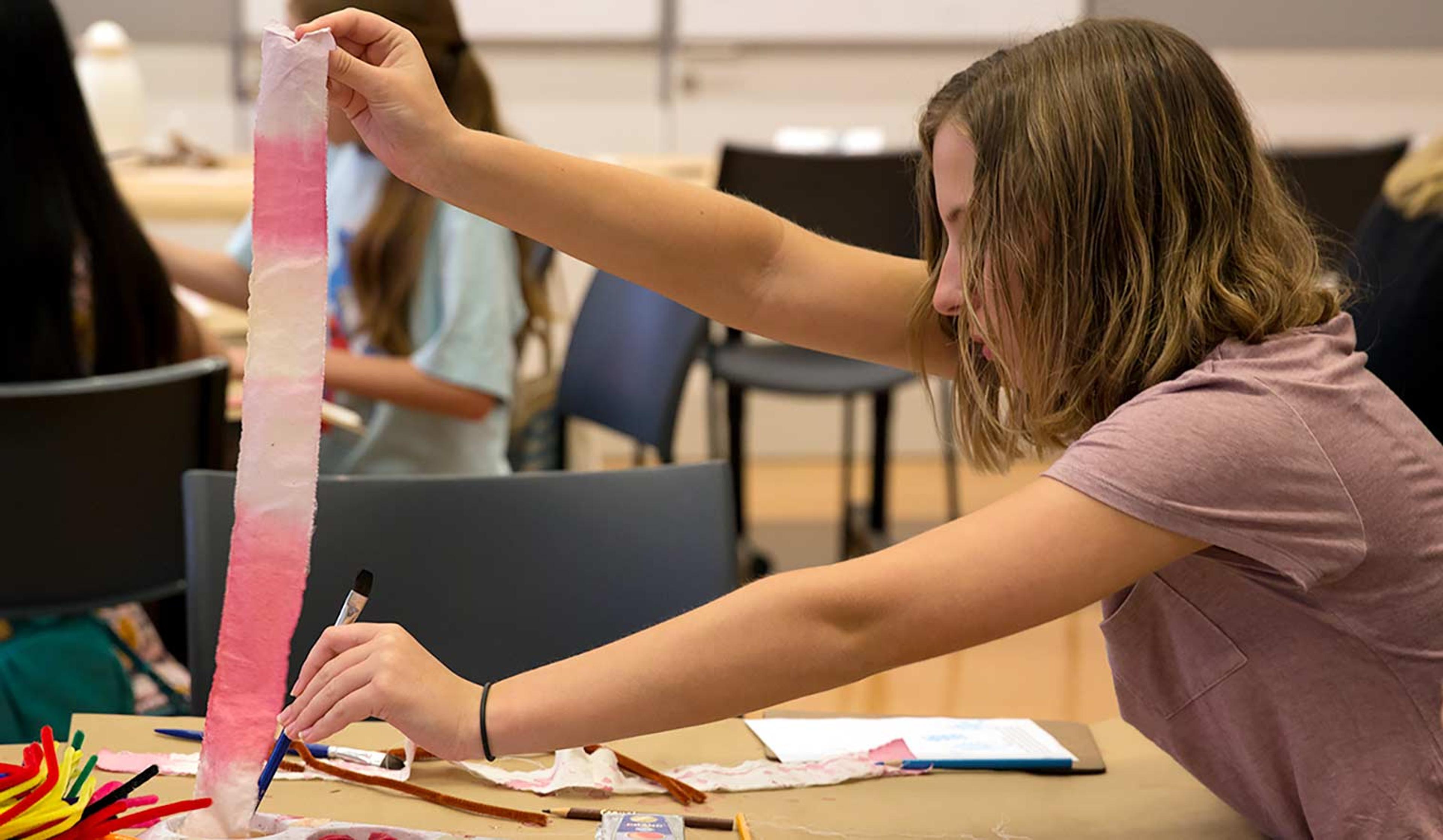 Teen colors strip of muslin cloth with dye made from fruits and vegetables.