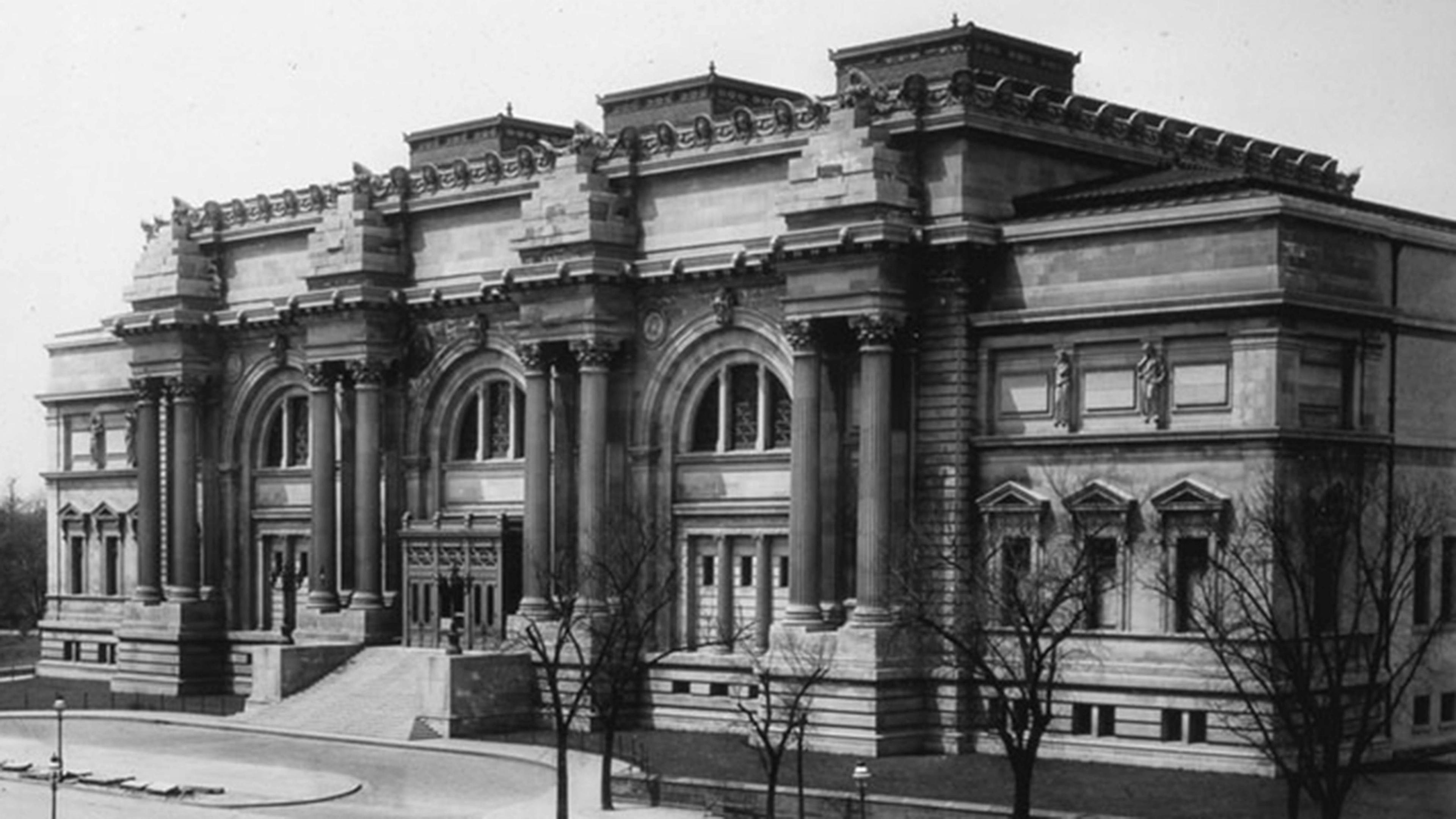Historic black and white photo of The Met building with columns and arched windows, surrounded by bare trees and a quiet street in front