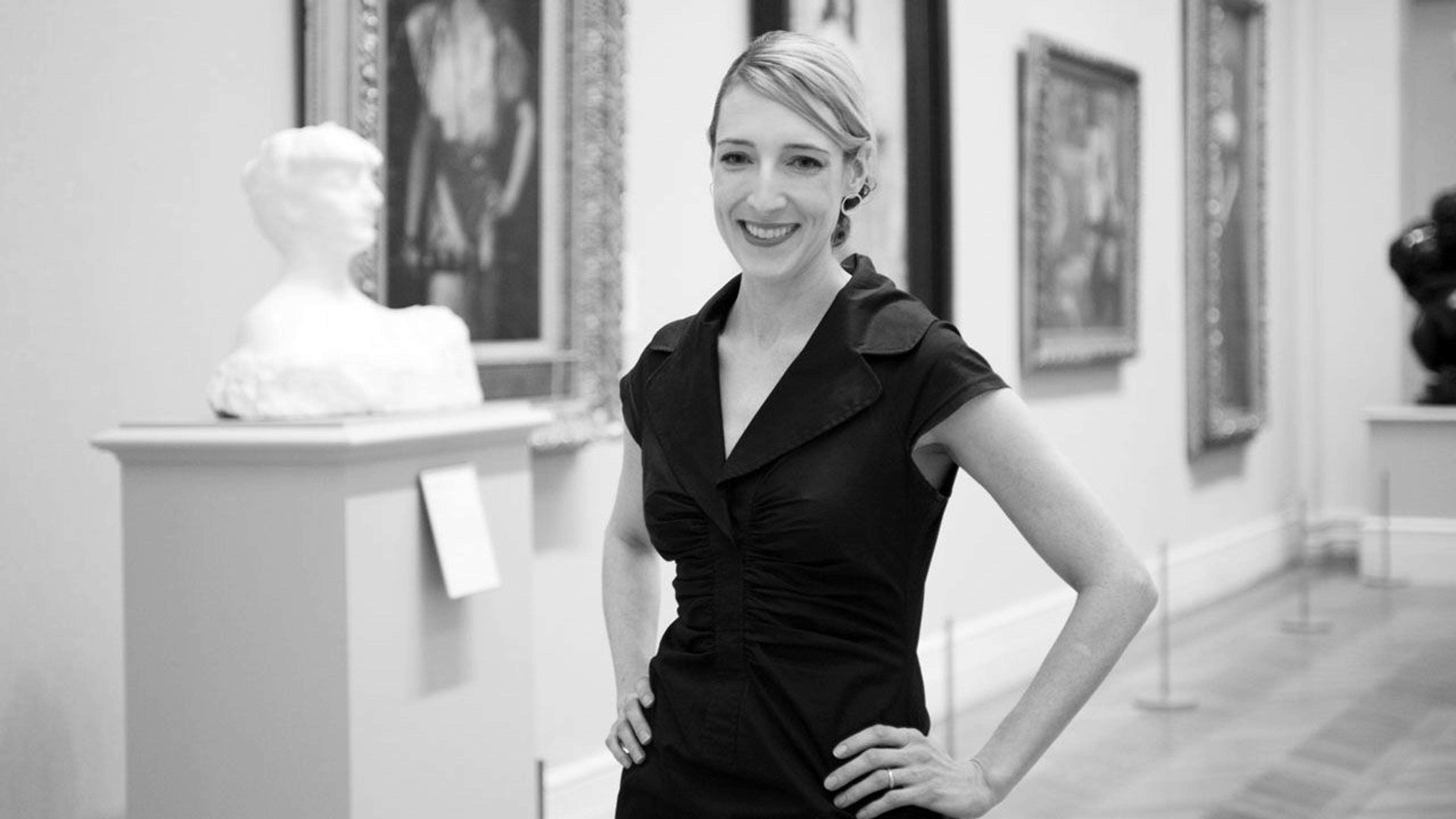 Black and white photograph of Masha Turchinsky standing in a gallery at The Met
