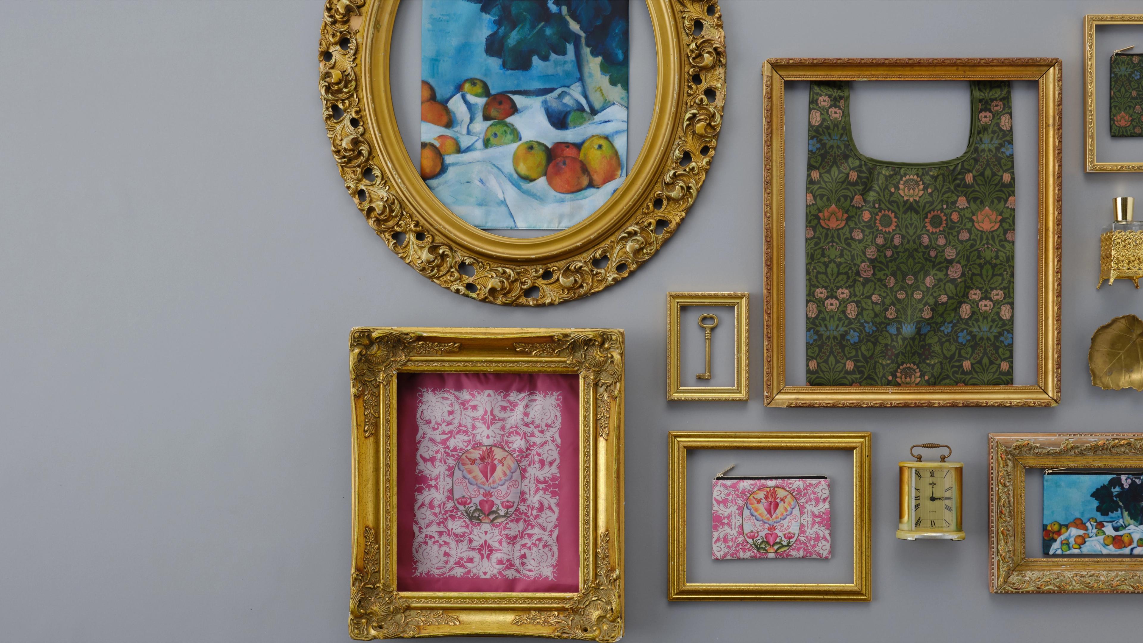 A collection of colorful artwork in gold frames mounted on a gray wall.