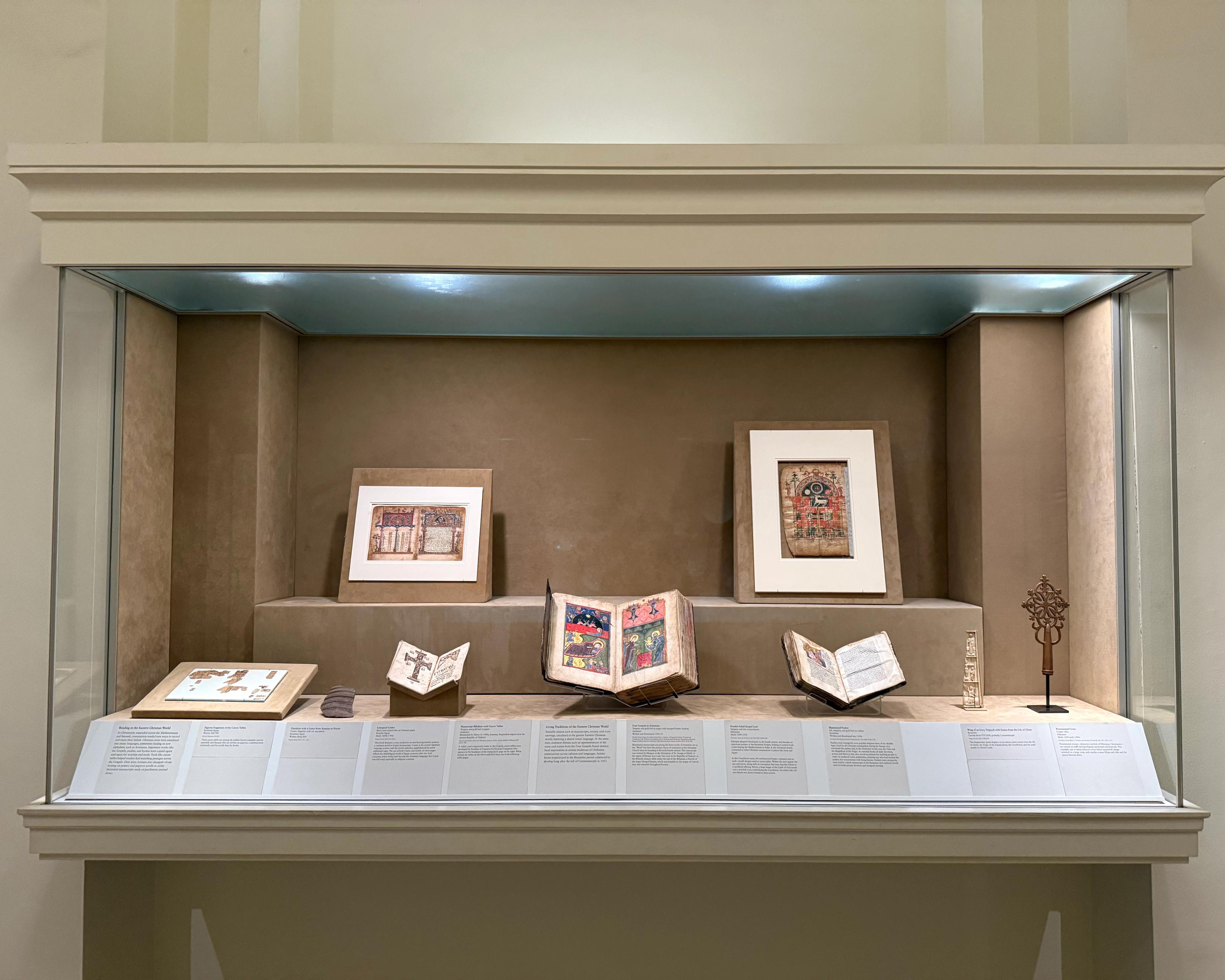 A display case exhibits manuscripts, works on paper, and metalwork objects
