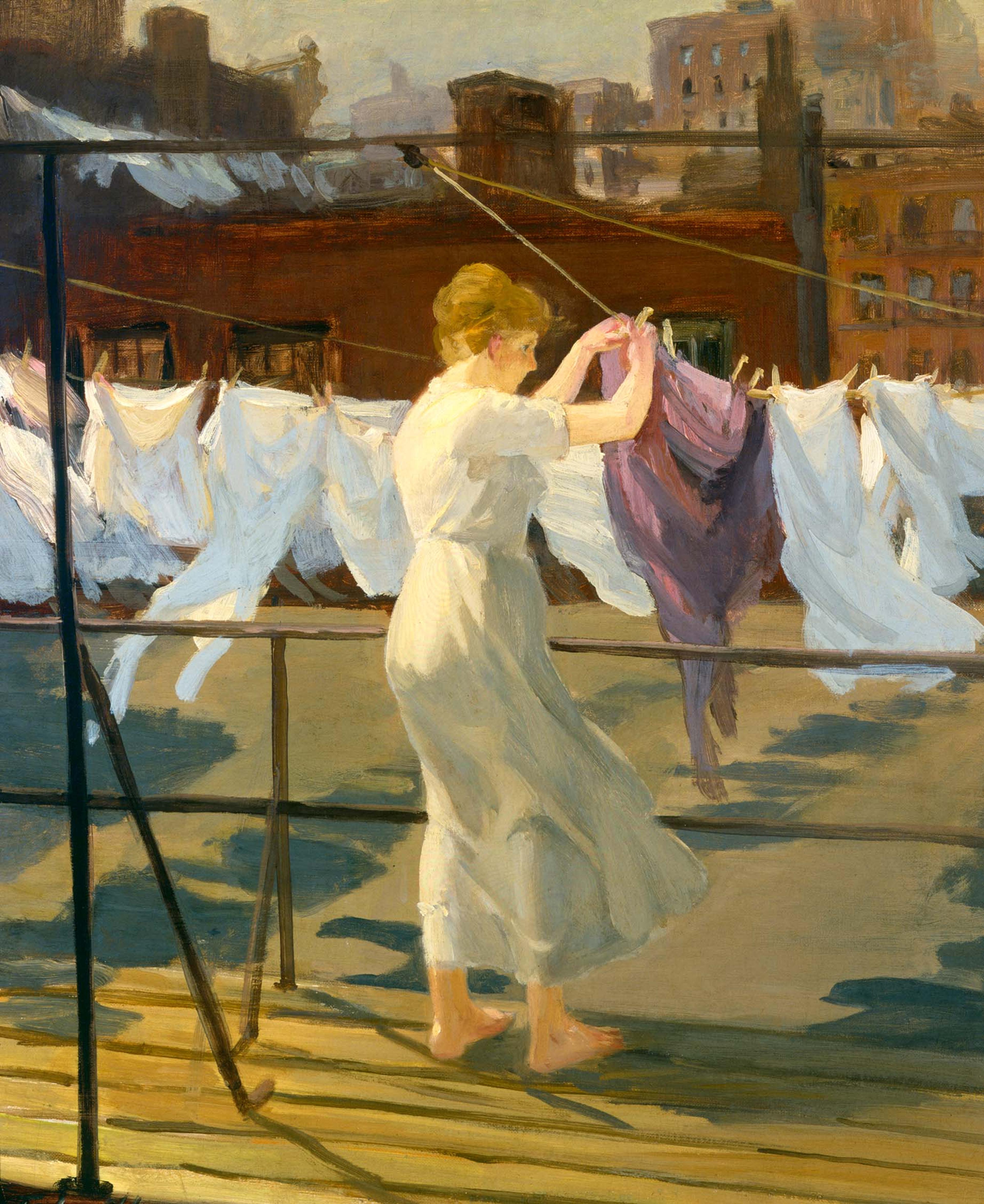 Color image of a woman hanging up wet laundry on a clothesline. 