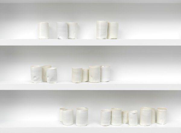 Three white shelves containing multiple white porcelain vessels by artist Edmund de Waal