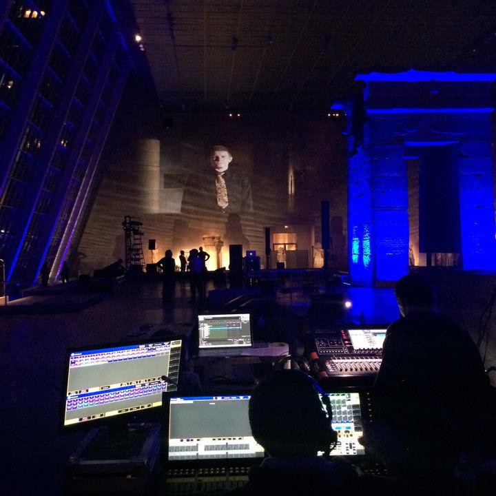 A view of a performance in The Met's Temple of Dendur, as seen from the technical crews perspective, showing the many computers and monitors needed to execute the performance