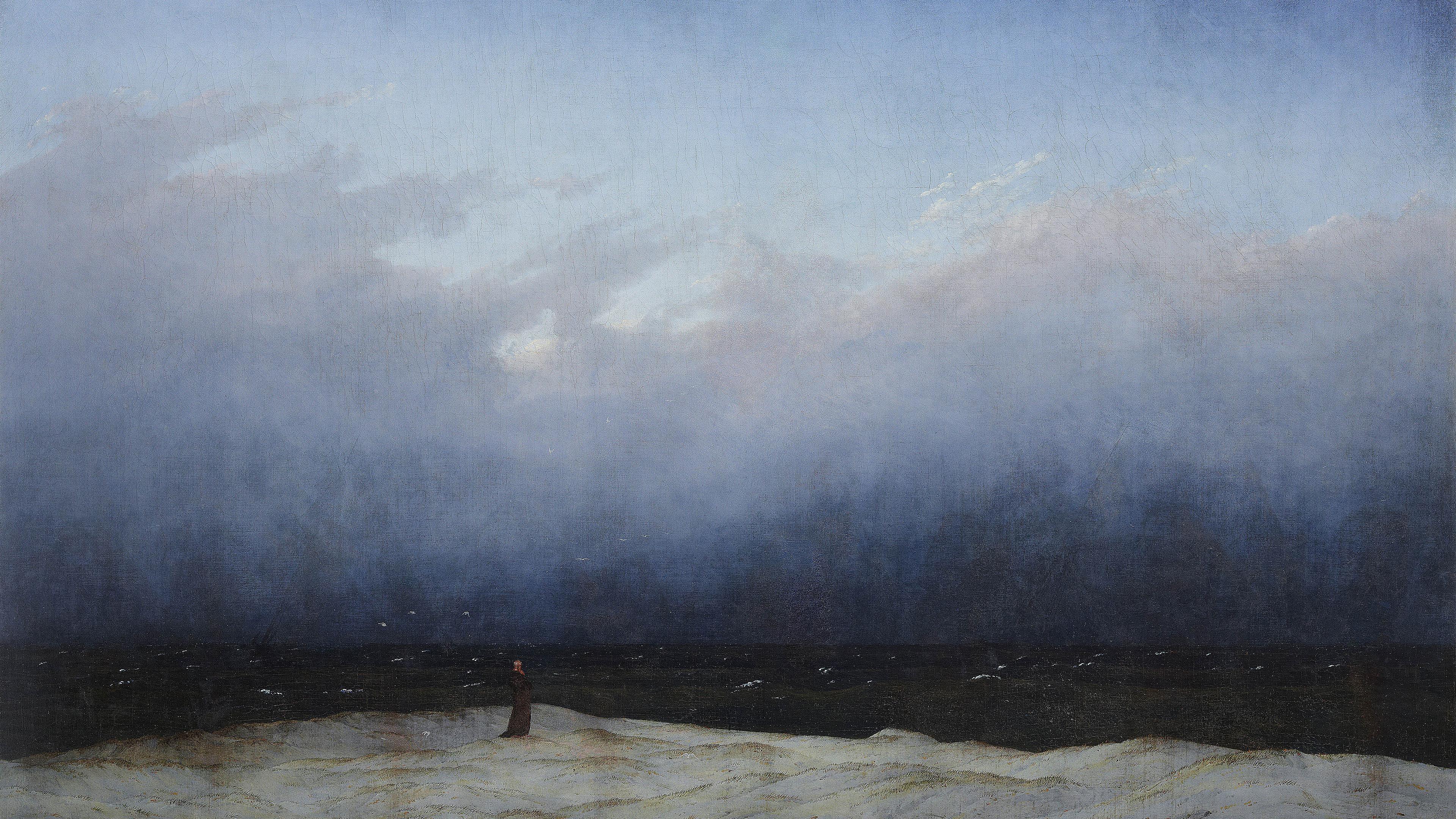 A solitary figure stands on a dune, gazing at the vast, dark sea under a cloudy sky.