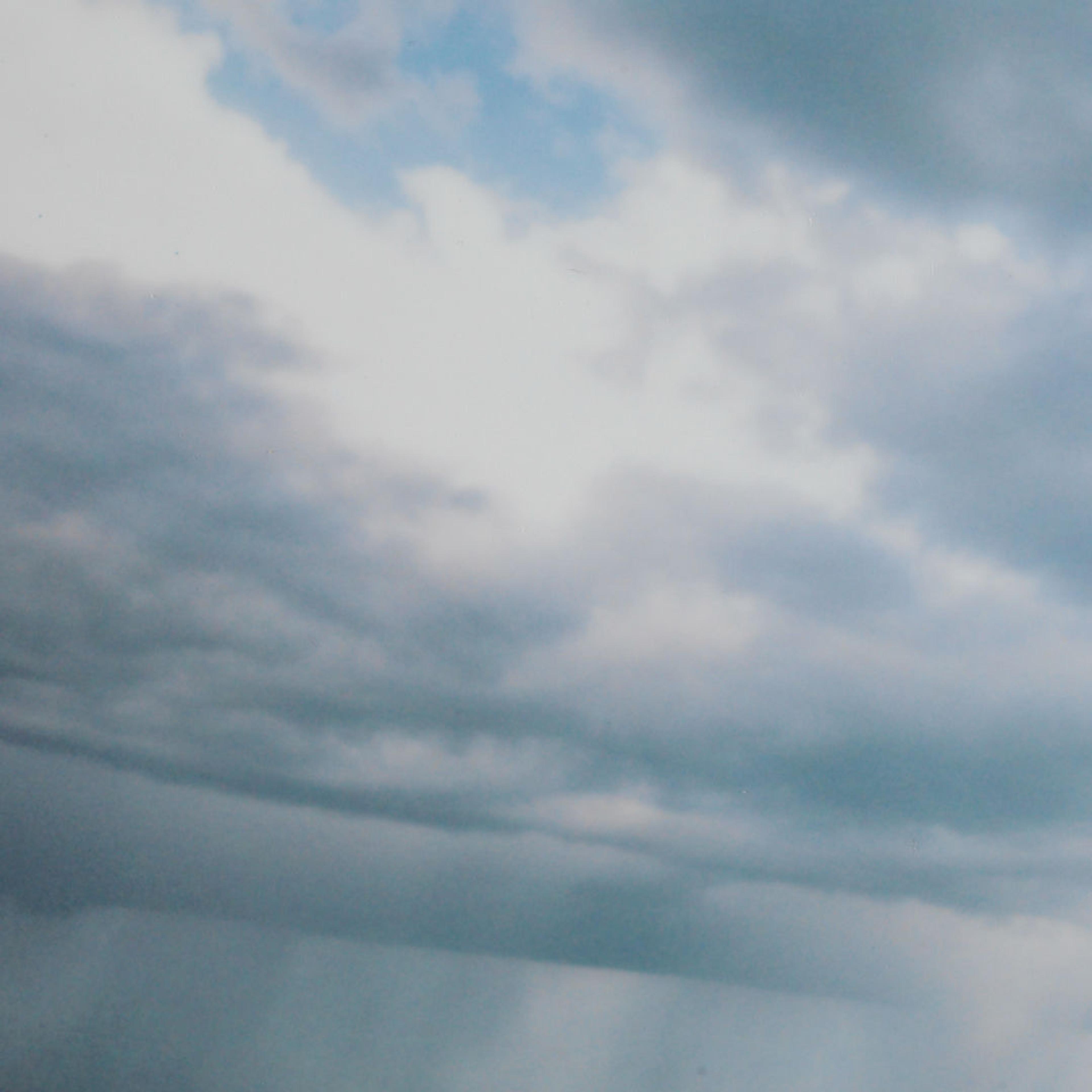 Sky with puffy blue and white clouds. A light blue sky peeks through the top right corner of the image.