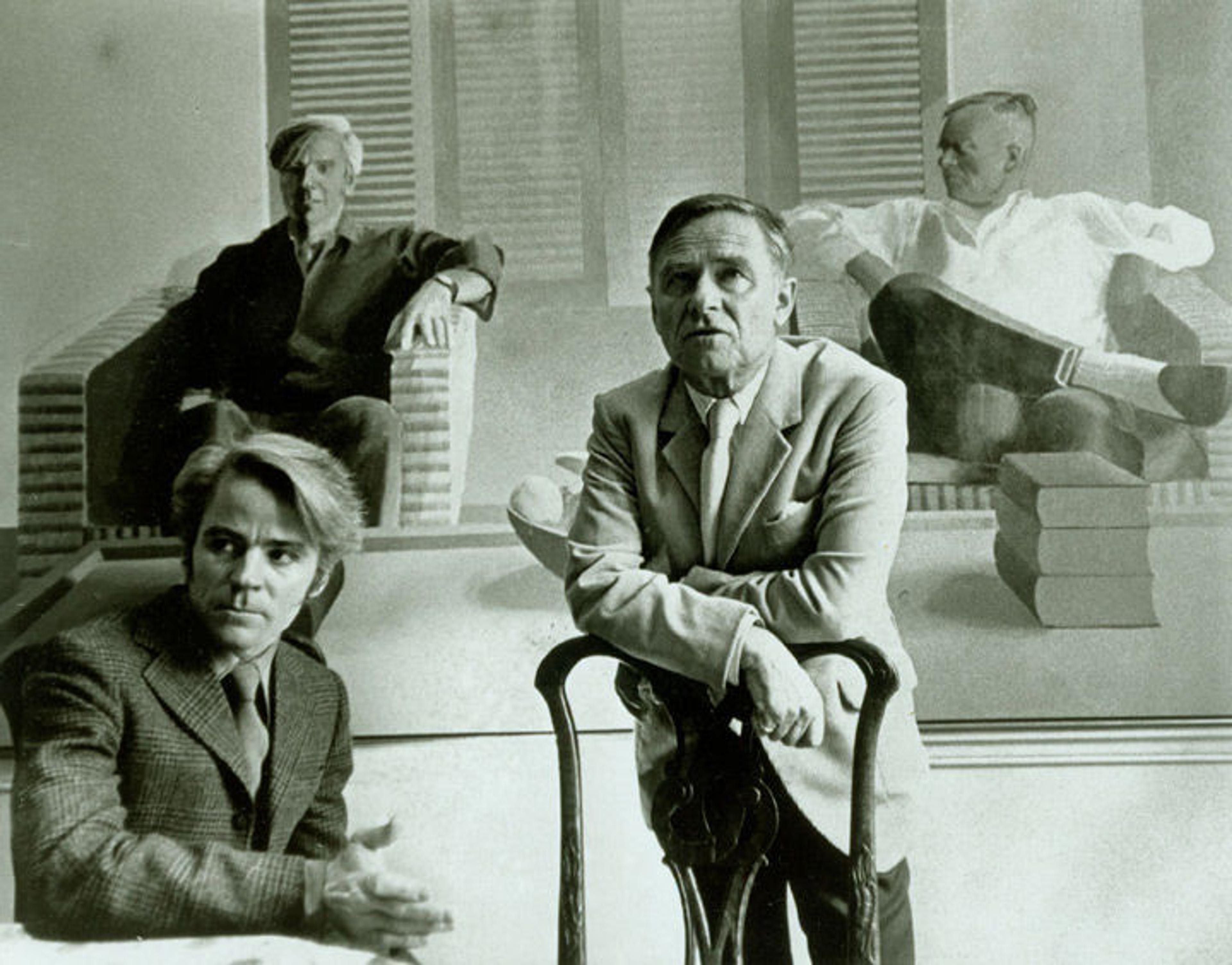 Black-and-white photograph of Christopher Isherwood (right) and Don Bachardy (left) in front of the double-portrait of them painted by David Hockney