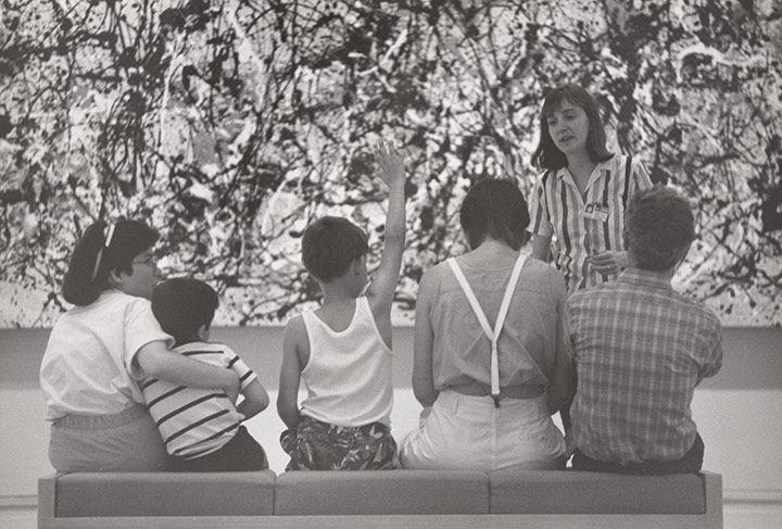 Archival photo of a group having a discussion in front of Jackson Pollock's Autumn Rhythm (Number 30).