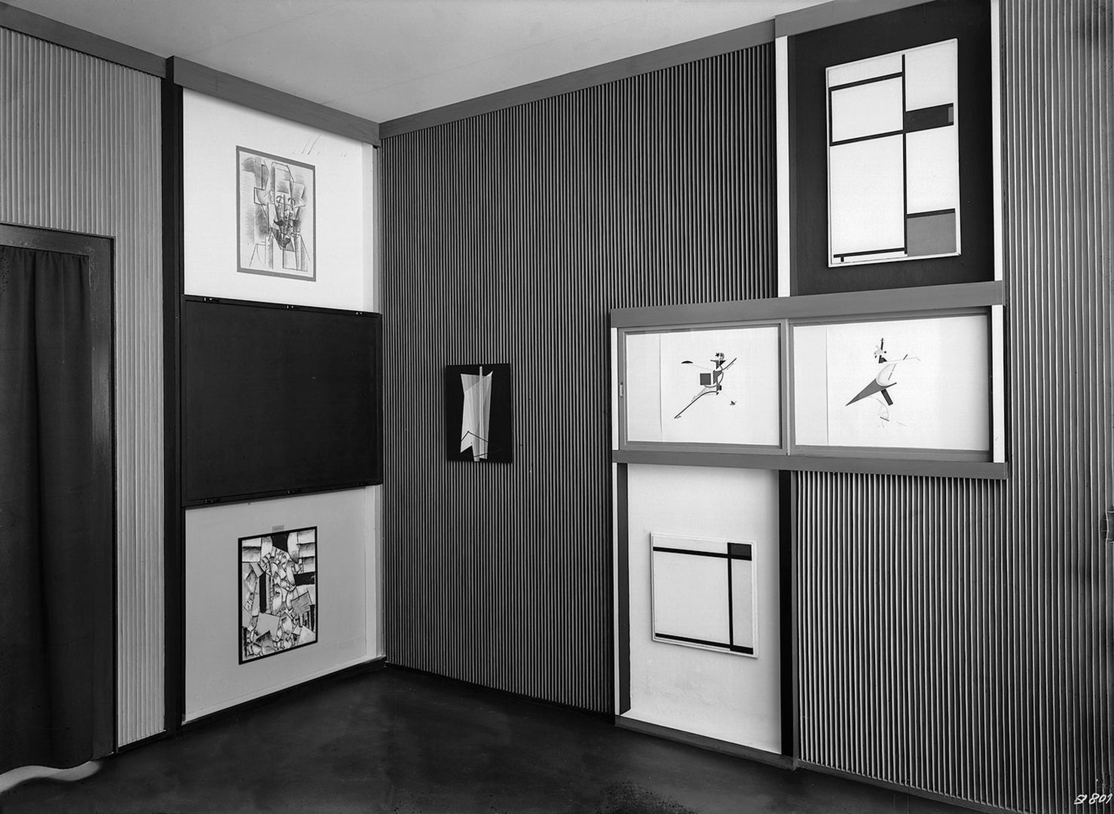 Black and white photo of room with paintings on wall