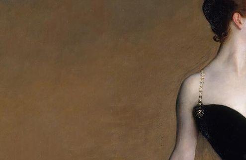 A cropped image of a woman in a gown from the side of the face to center of the chest.