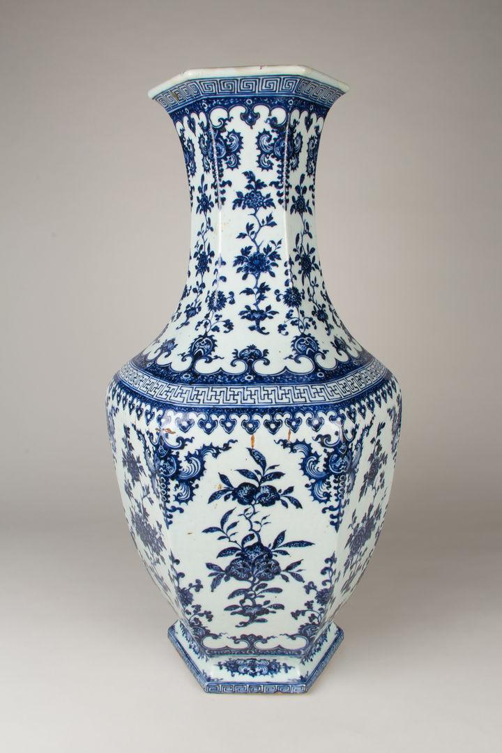 Photograph of a large Chinese vase against a grey backdrop. There are decorative patterns on the porcelain in blue and white.