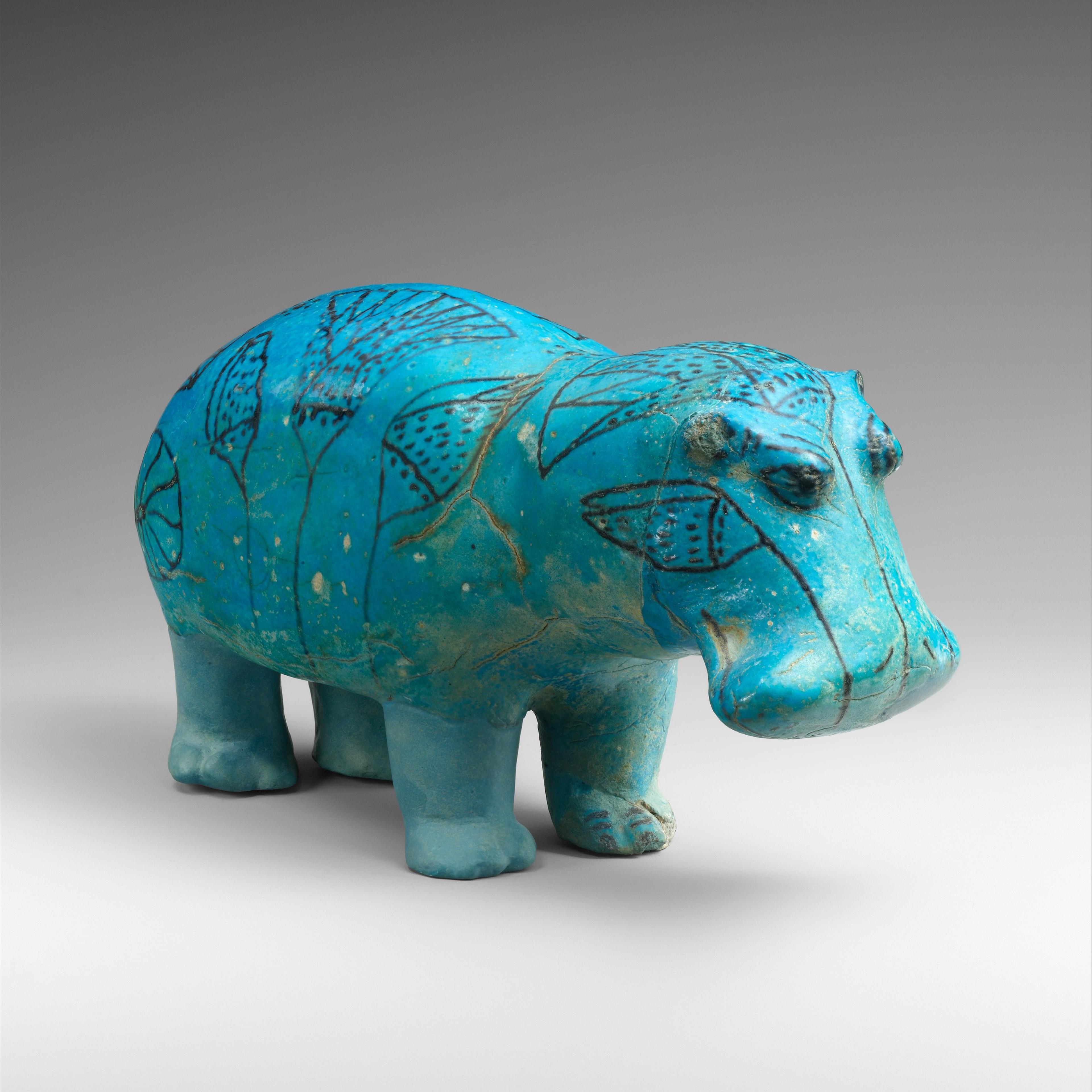 Faience hippopotamus figurine in vibrant turquoise with intricate patterns of leaves over the body and head.