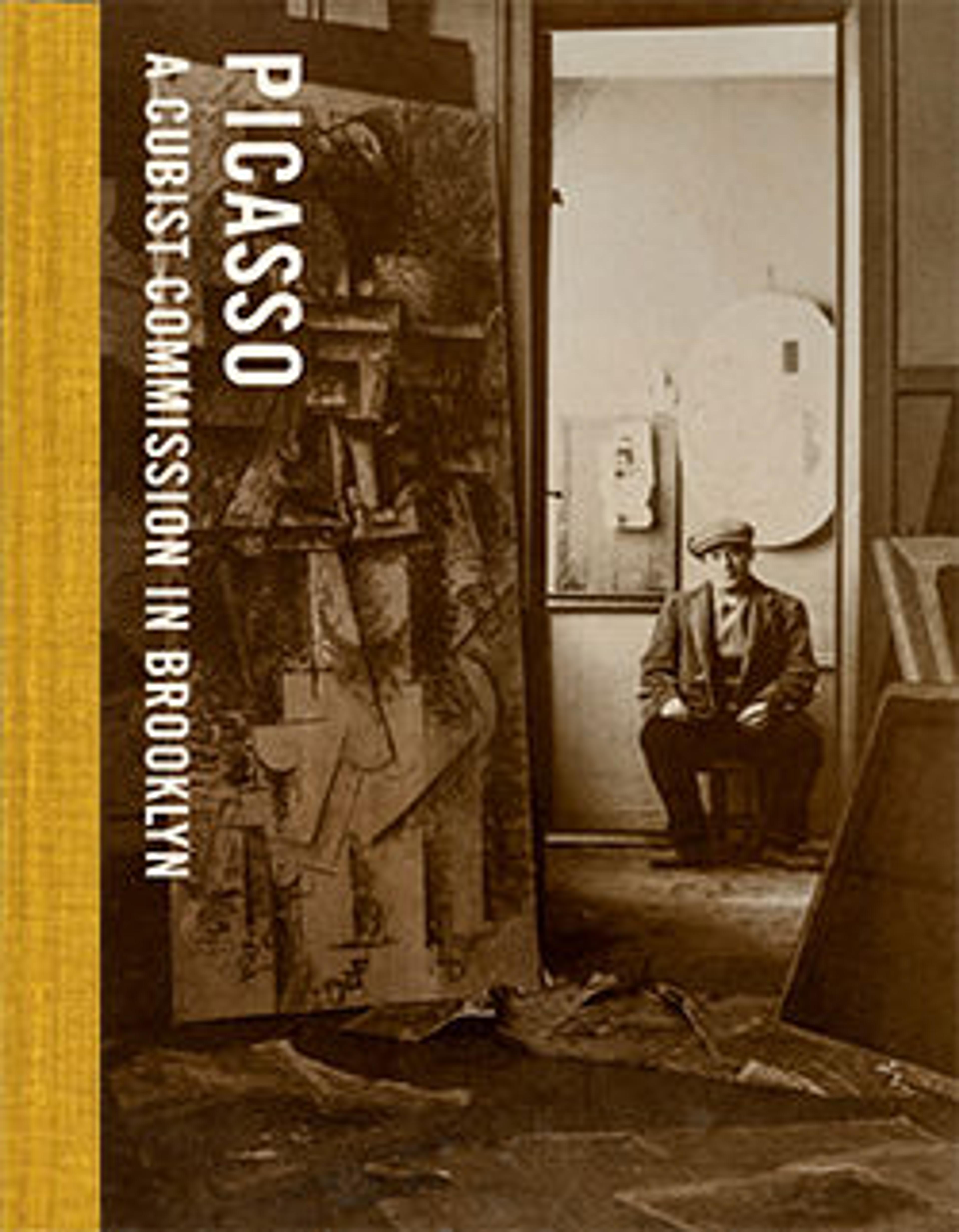 a sepia-toned photograph of a studio and a man sitting through a doorway next to which leans a large cubist painting