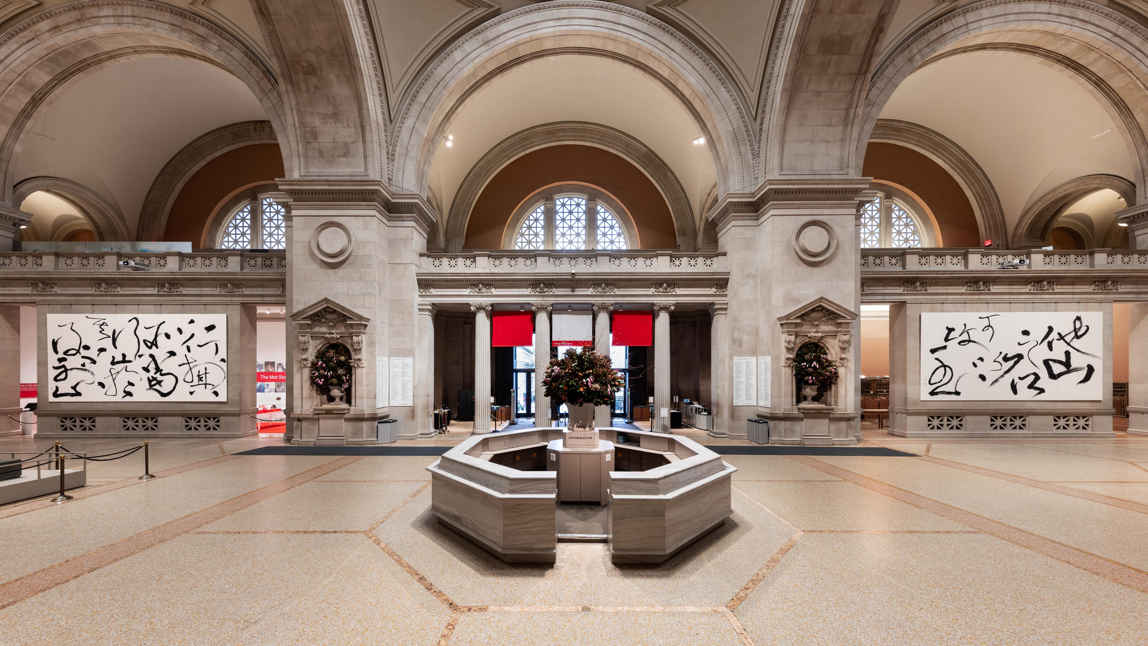 The interior of a museum with two large calligraphic paintings flanking a central booth