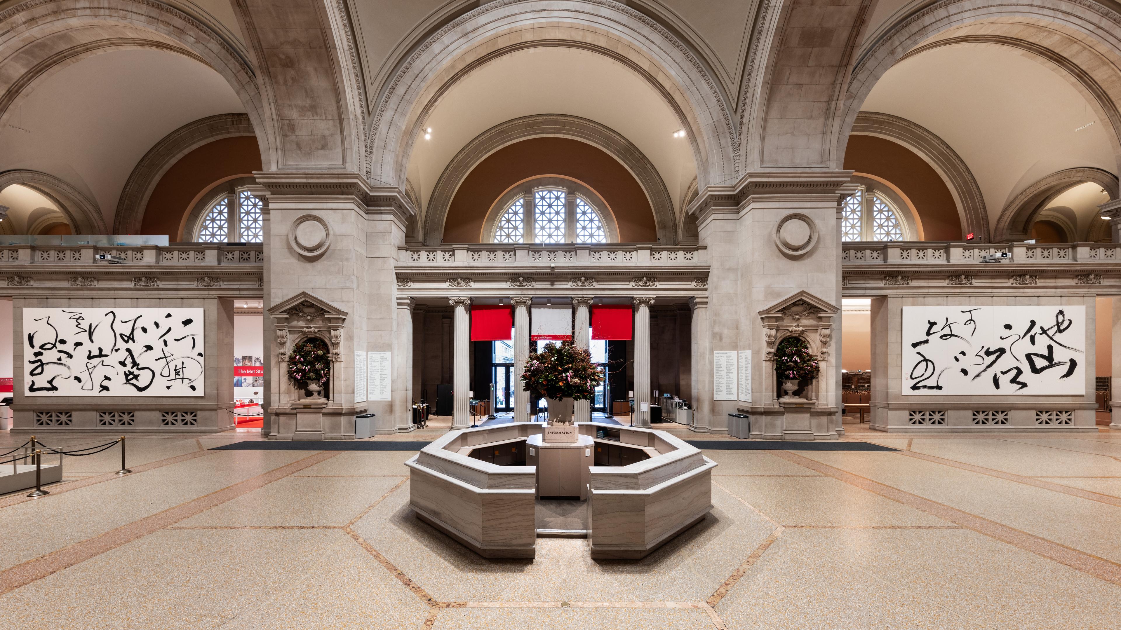 The interior of a museum with two large calligraphic paintings flanking a central booth