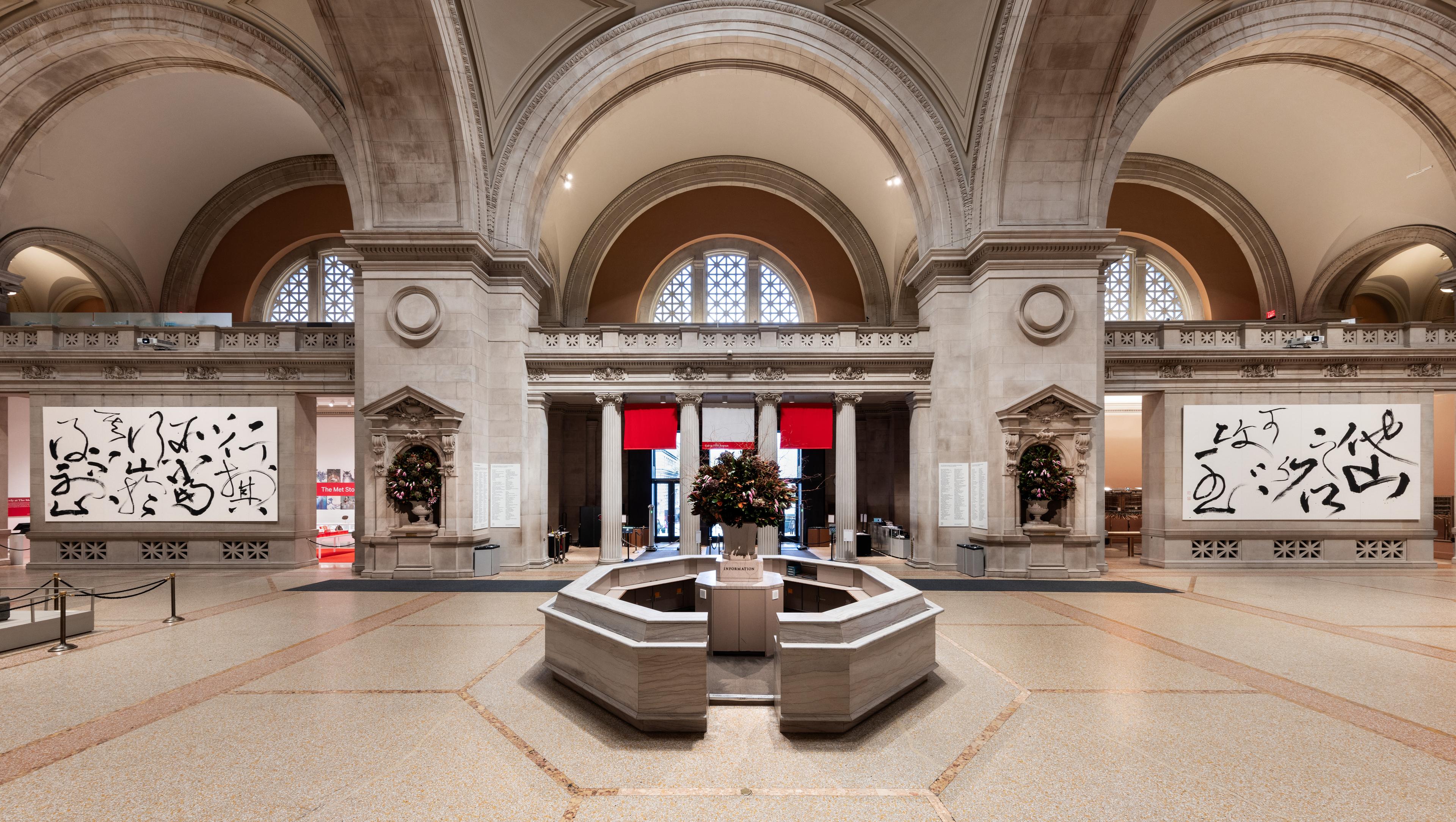 The interior of a museum with two large calligraphic paintings flanking a central booth