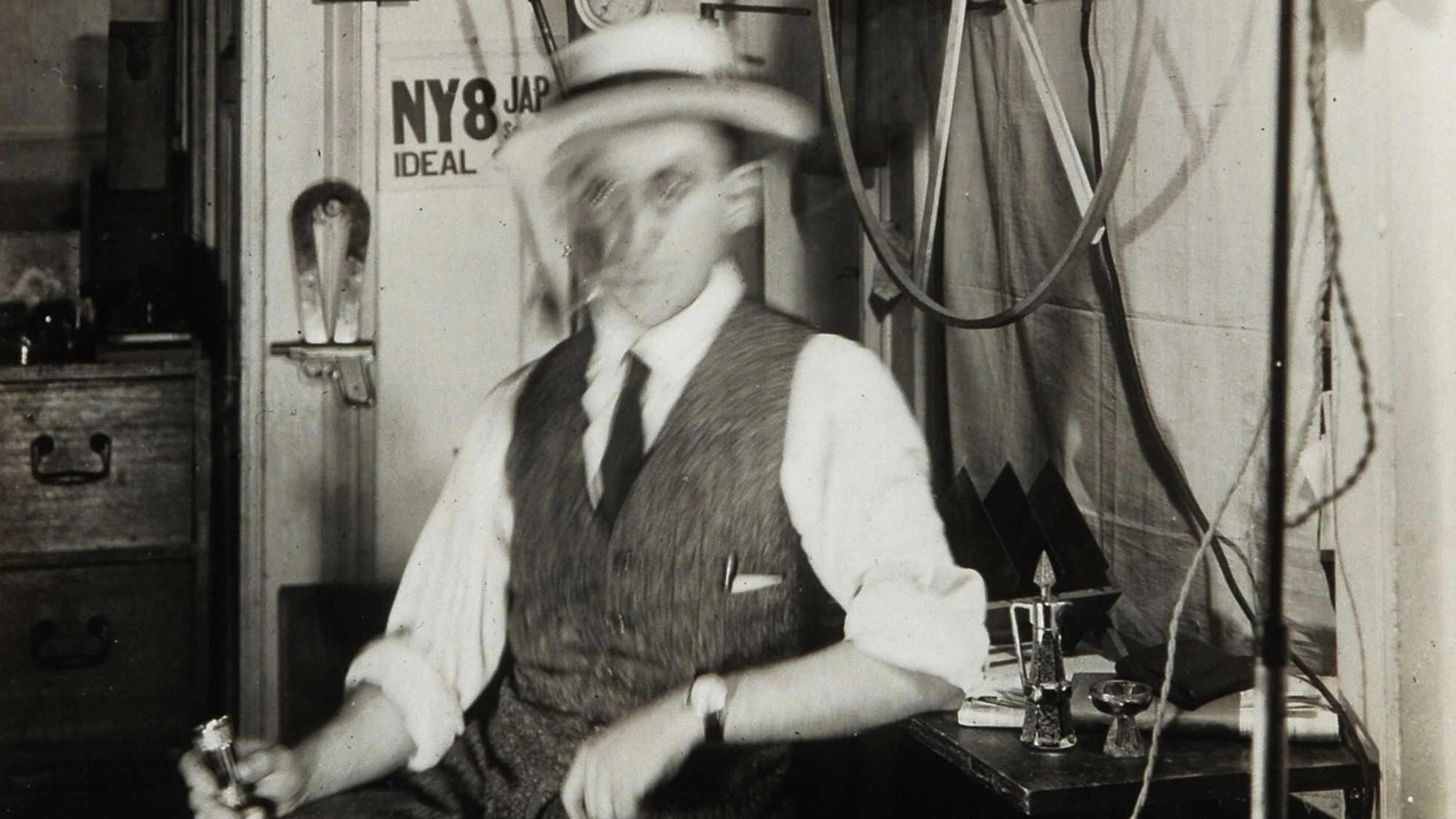 Black-and-white photograph of a man smoking and wearing a hat and glasses.