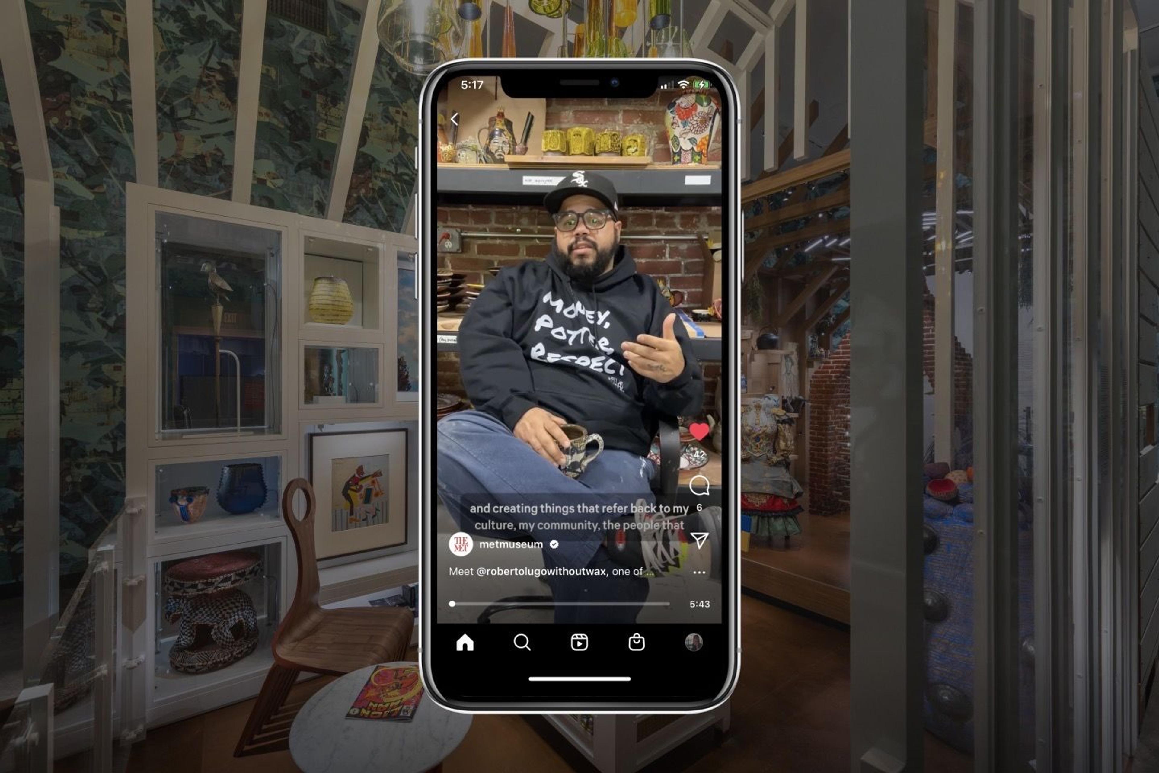 The artist Roberto Lugo is seen on an iPhone screen against a backdrop of the Afrofuturist period room currently installed at The Met.