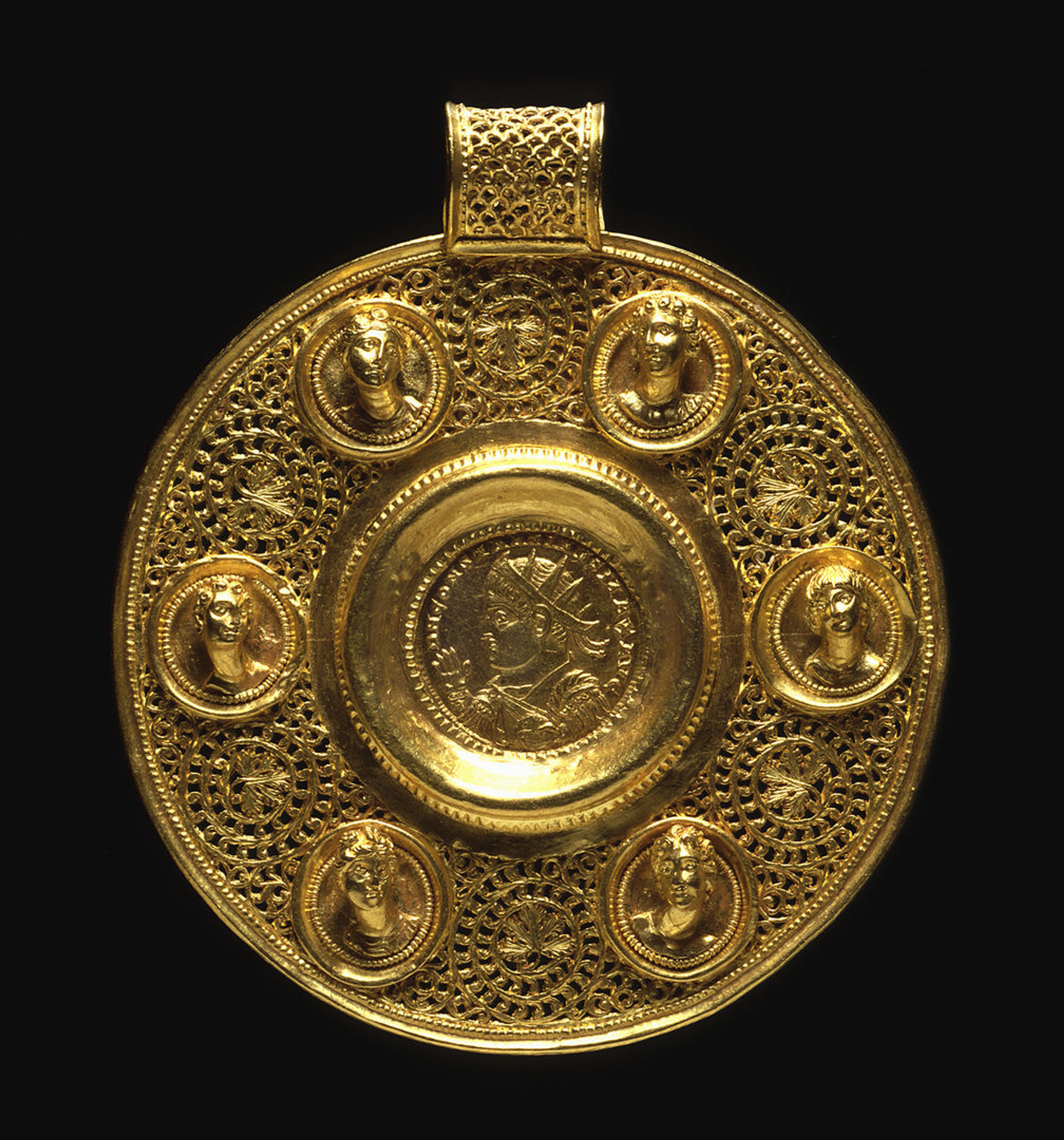 A gold Circular Pendant with Double Solidus of Constantine I with six female reliefs of faces surrounding him coming out of the gold.