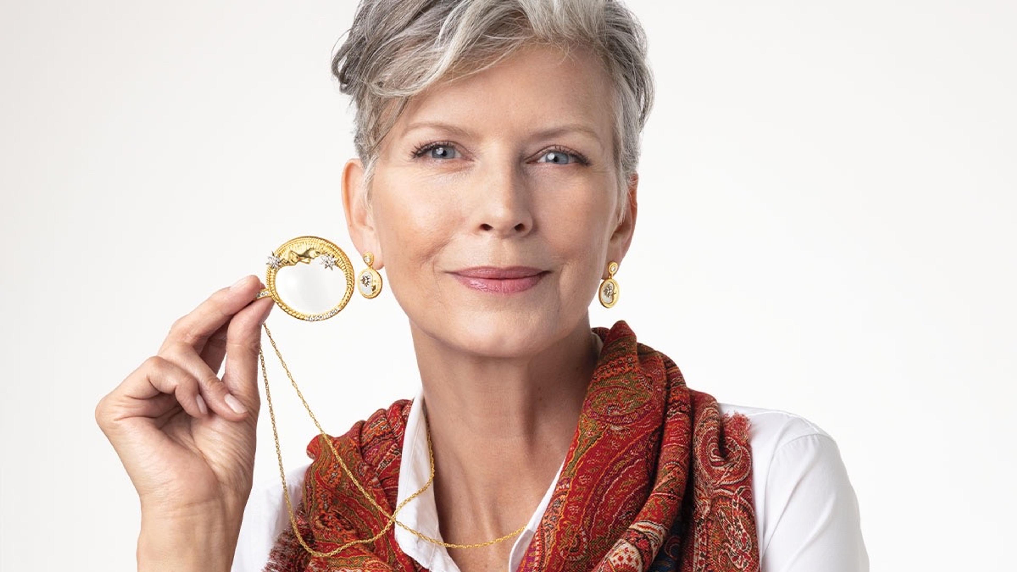 A woman with a red scarf holding a piece of jewelry. 