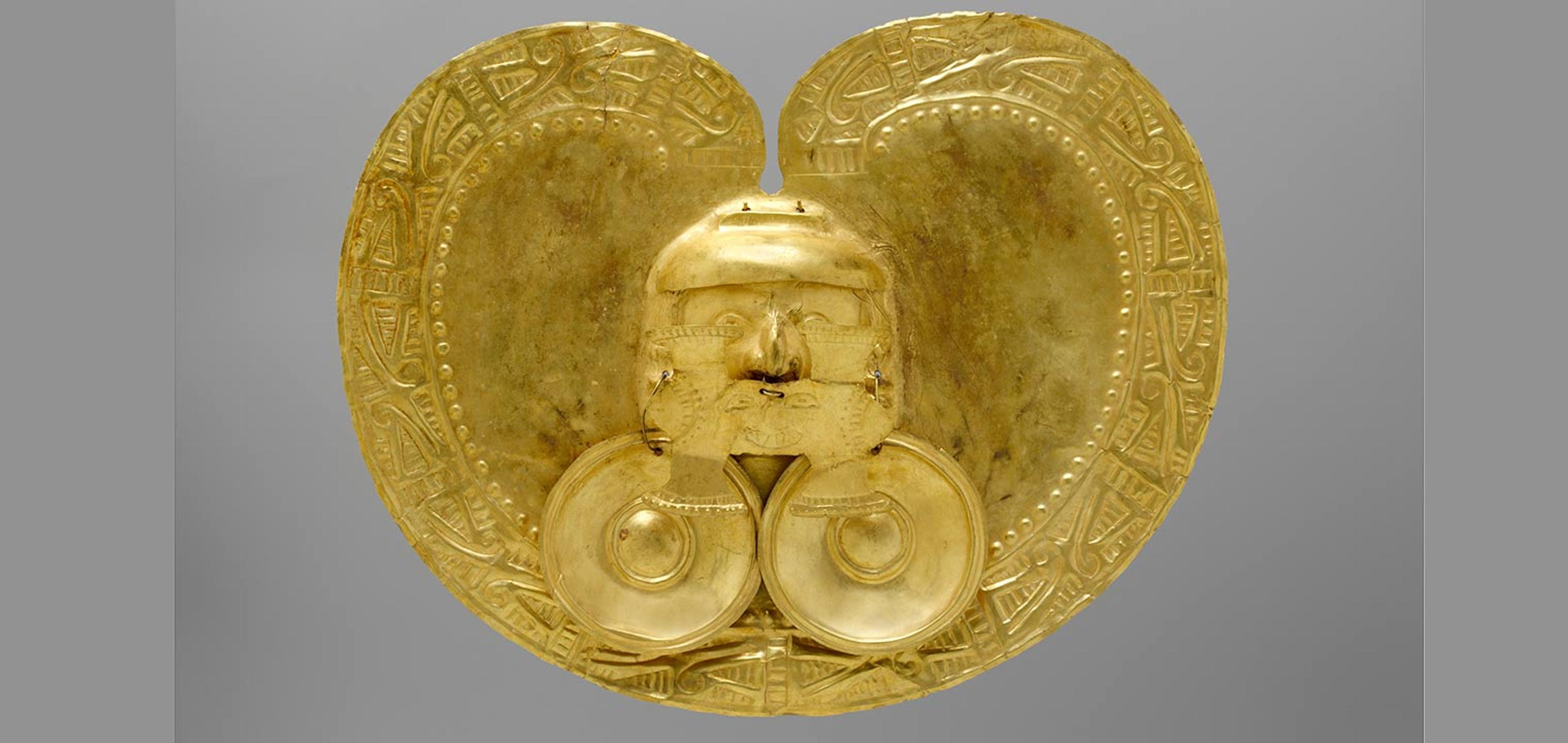 A  heart-shaped gold pendant with a relief of a  face in the center and two golden circles hanging off of the face's ears.