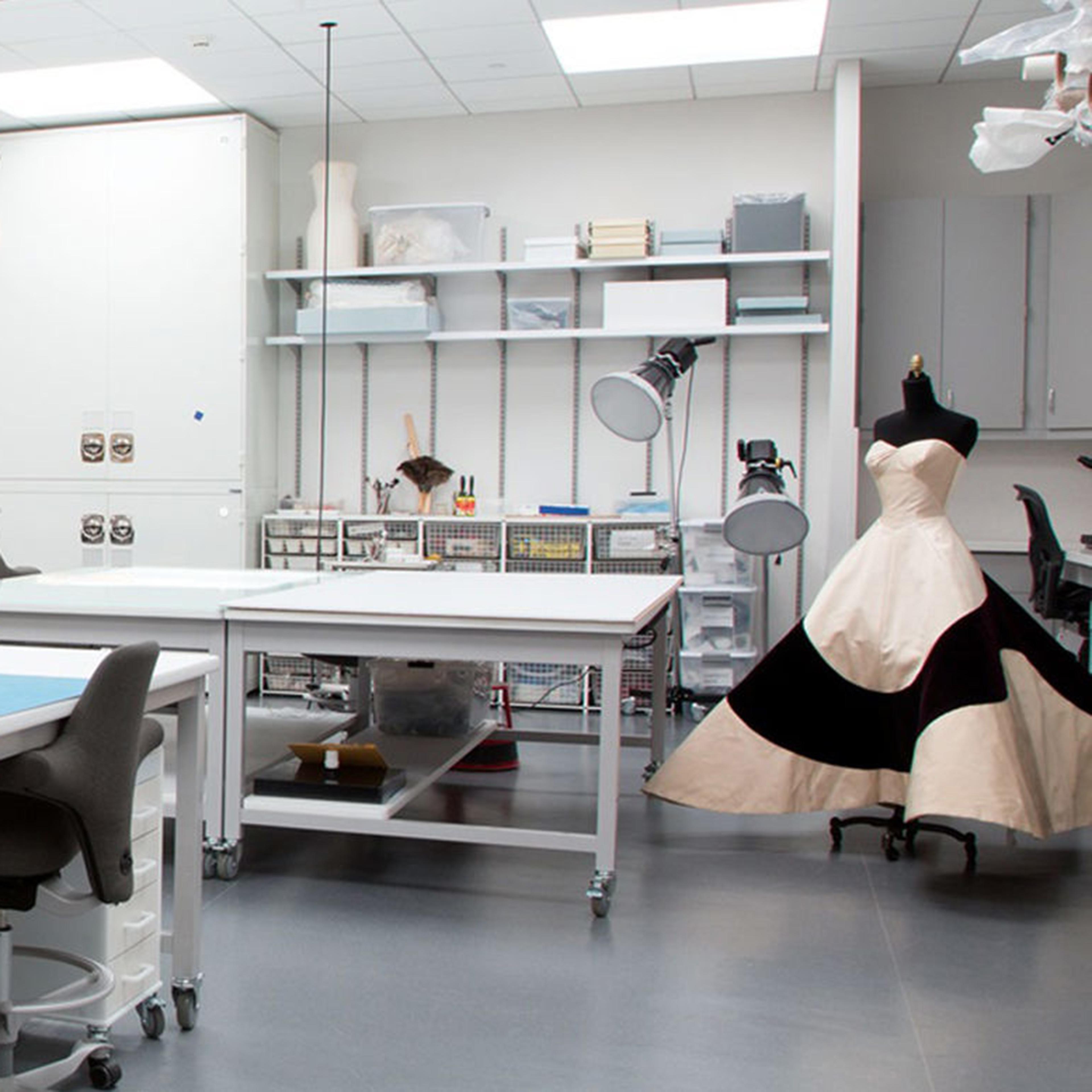 View of the Costume Institute Conservation lab, showing various examination tables, shelves of instruments, and a Charles James couture ballgown in the corner