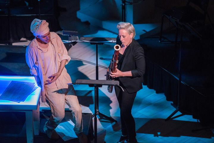A singer wearing white clothing and a turban performs alongside a bassoonist wearing all black