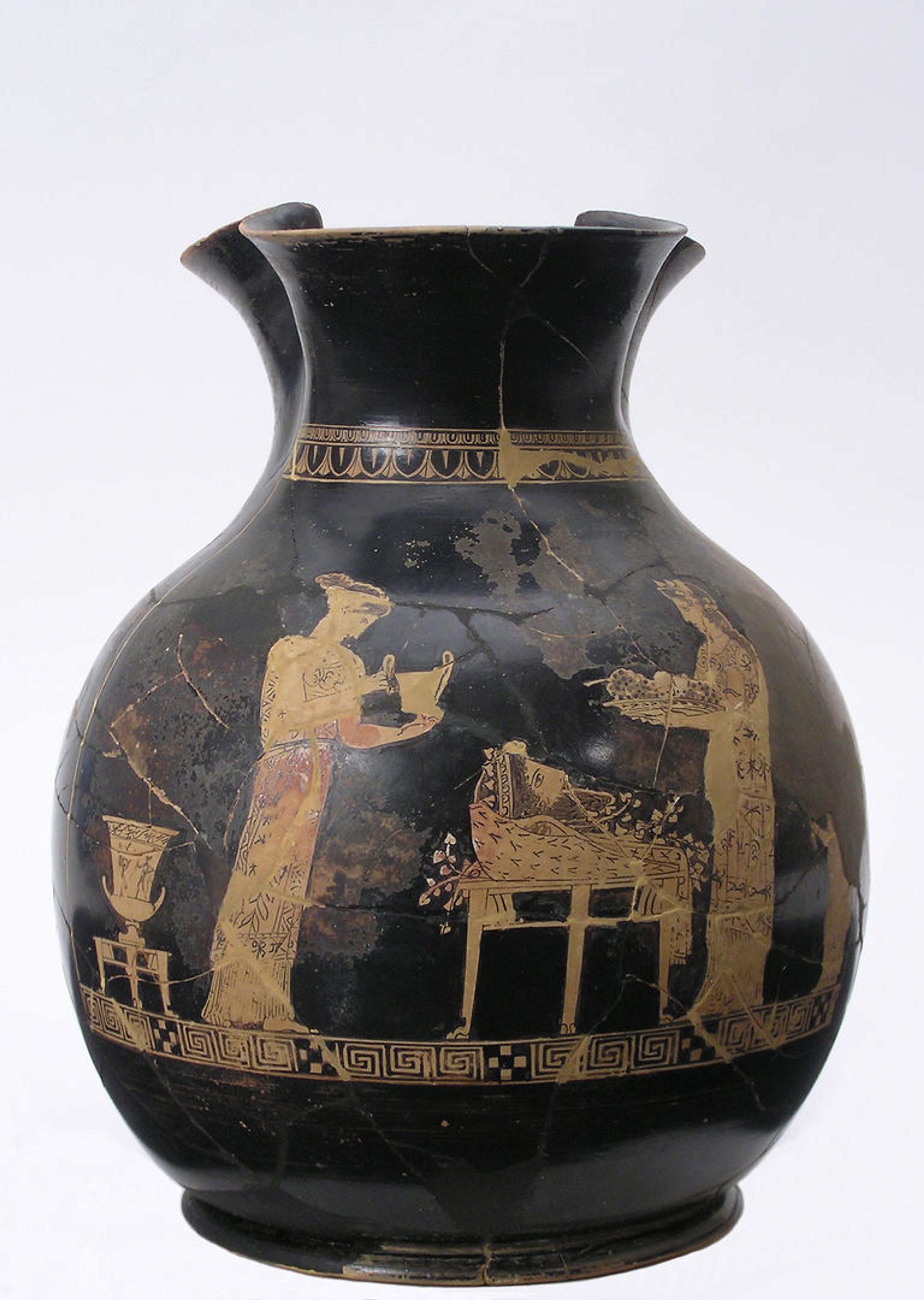 Black jug depicting preparations for Dionysos’s festival. In the scene, two women stand over a basket that contains the god's mask.