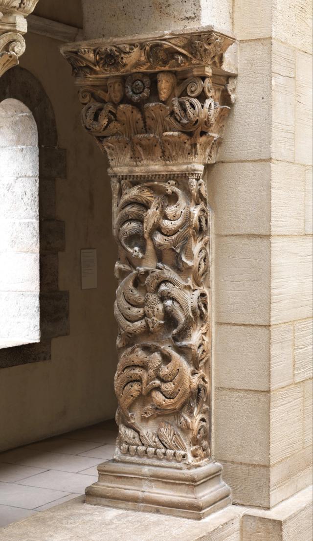 Stone column with elaborate carvings of intertwined foliage.