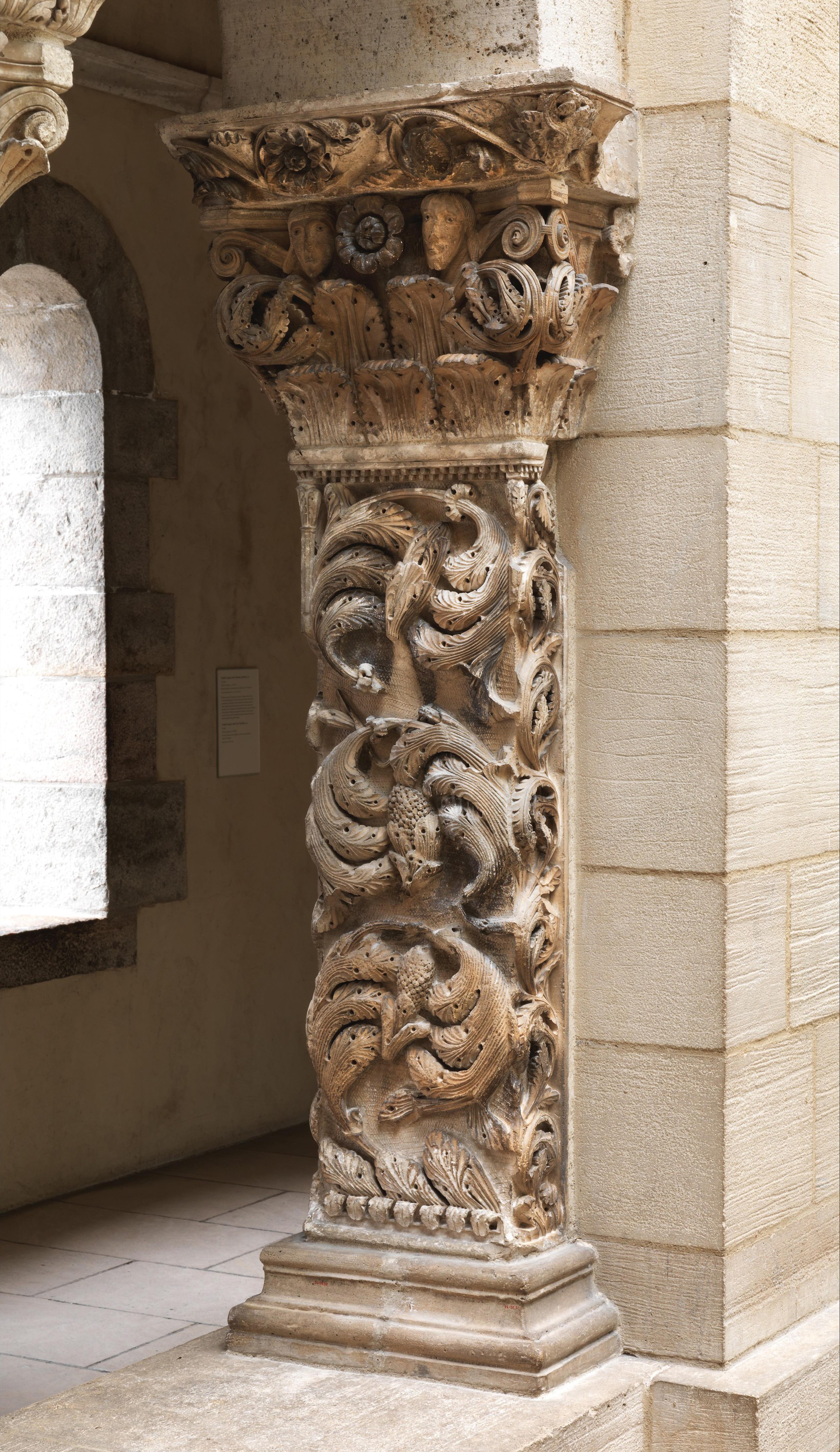 Stone column with elaborate carvings of intertwined foliage.