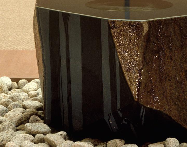 Detail of Isamu Noguchi's Water Stone showing the bottom of the fountain sitting on a bed of river stones.