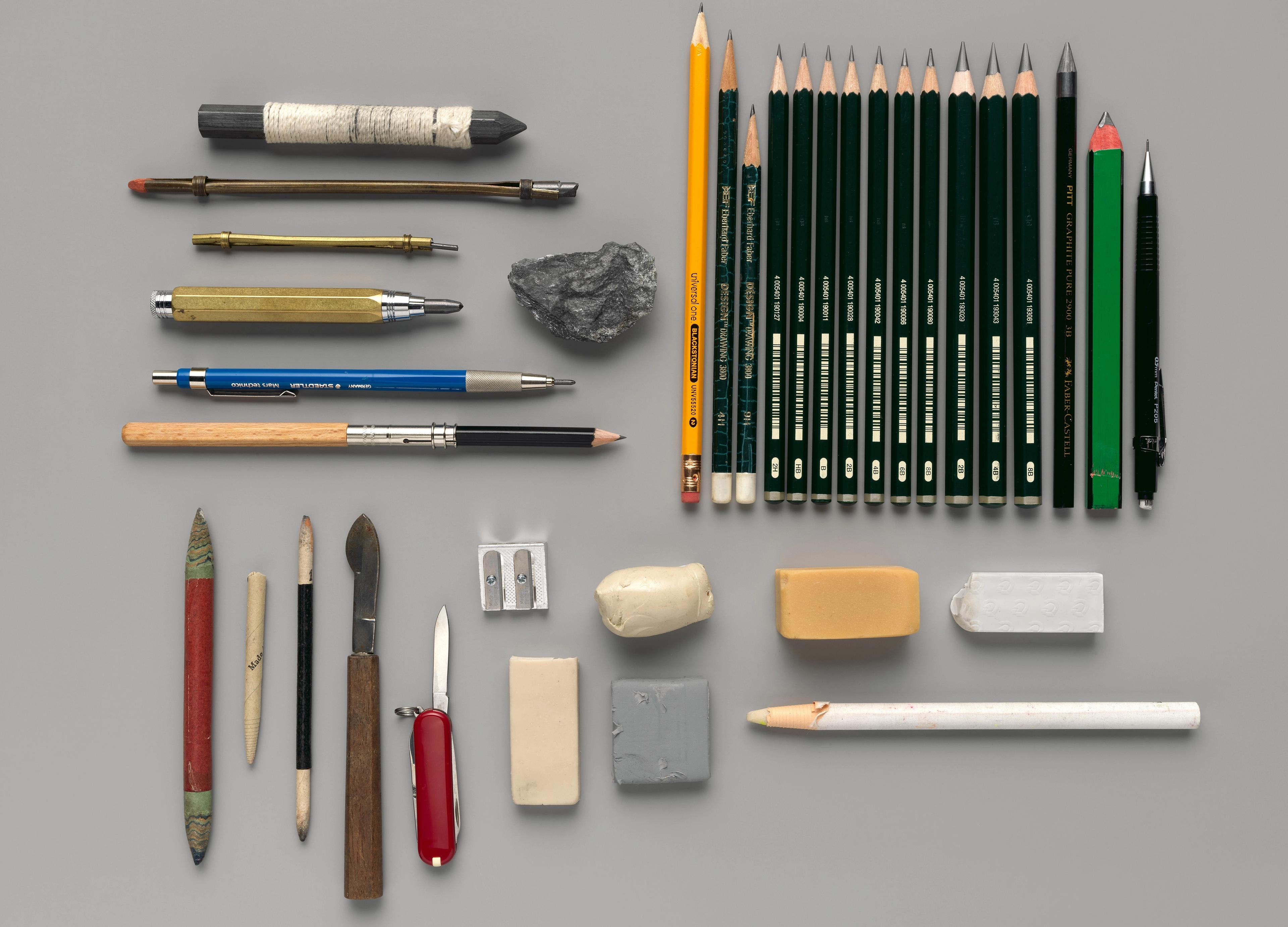 An artful arrangement of pencils, erasers, raw graphite, and other drawing implements.