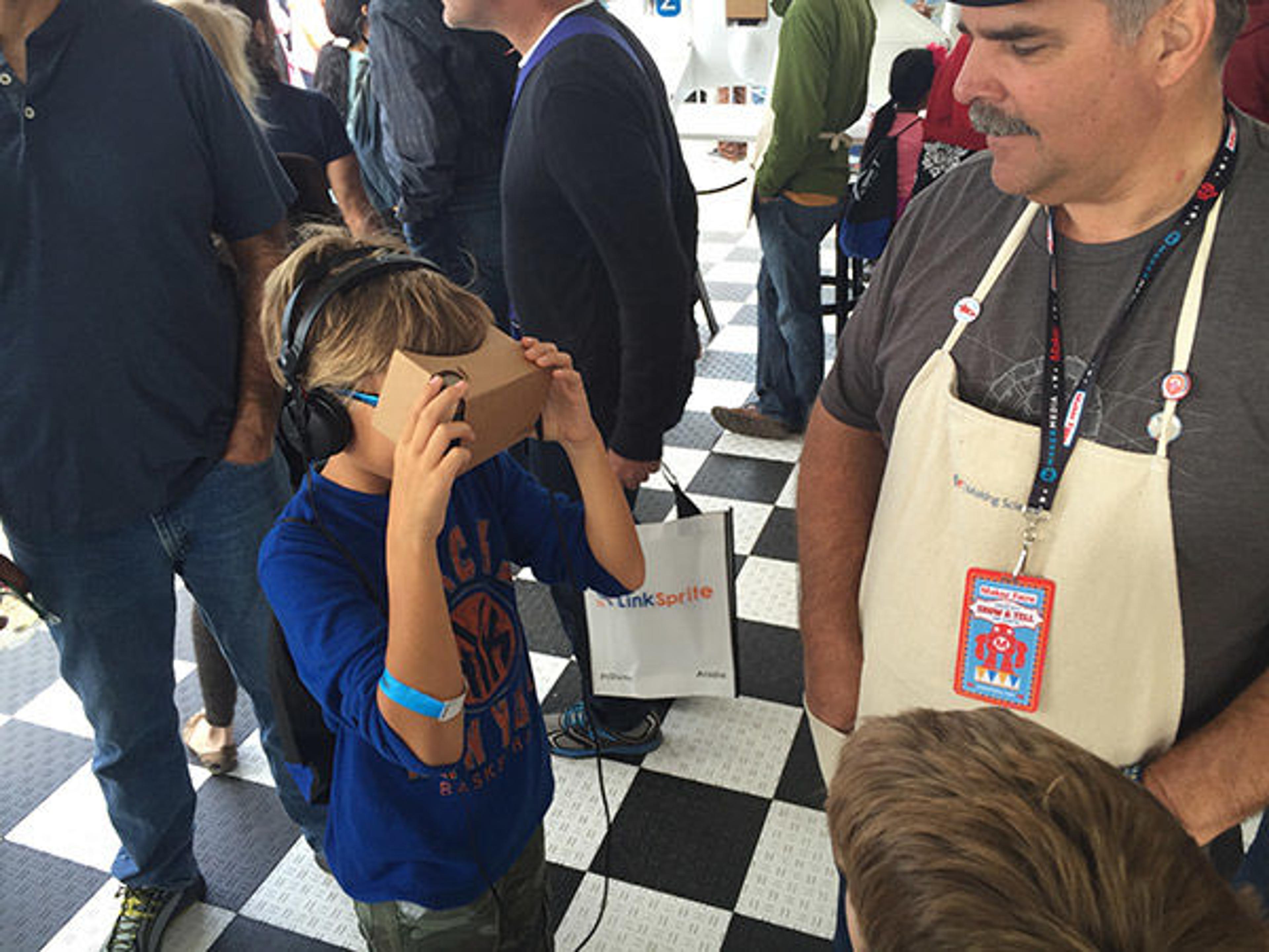 A kid holds cardboard glasses over his eyes.