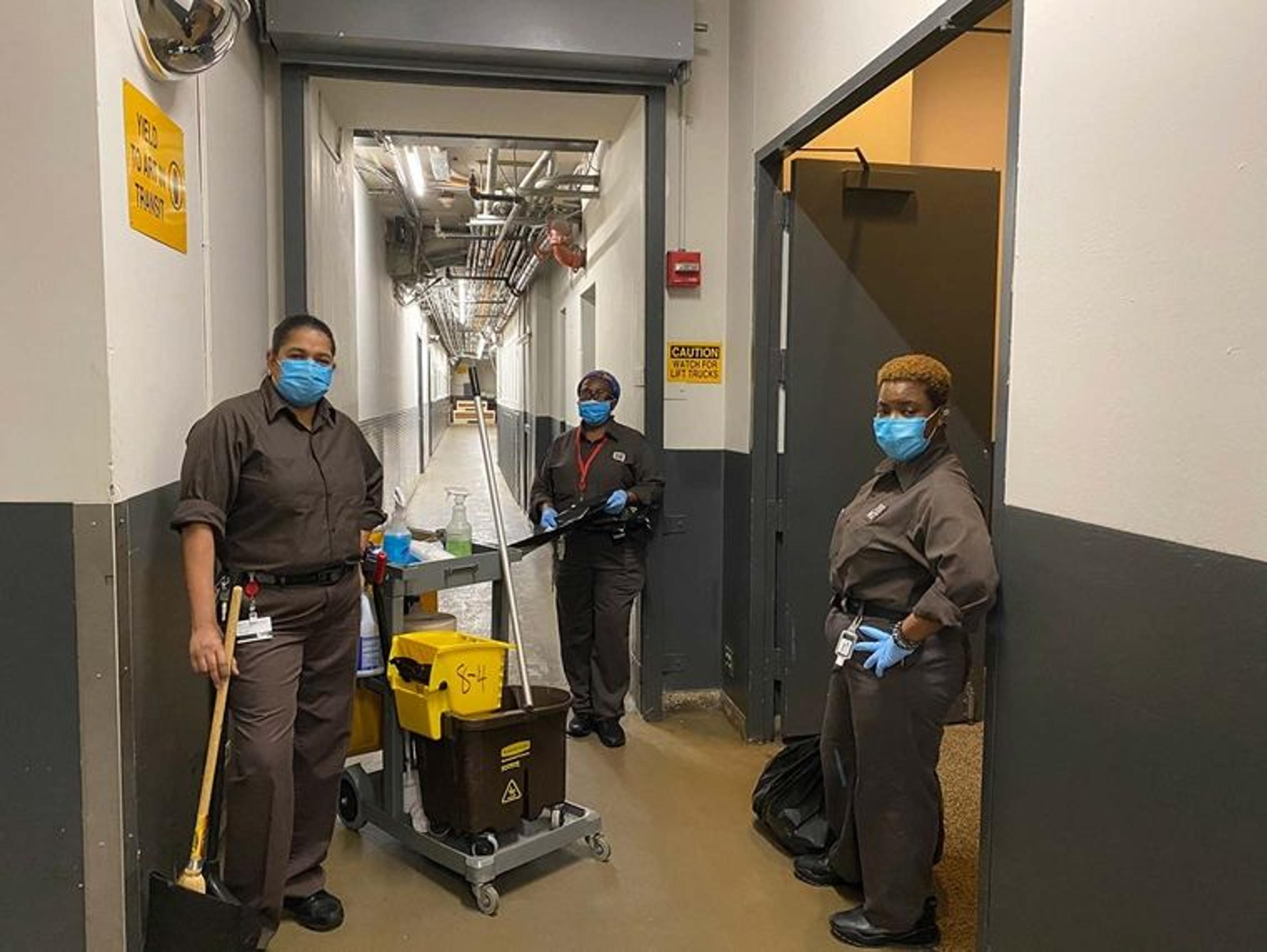Three members of The Met's custodial staff wear face masks as they prepare to clean the building.