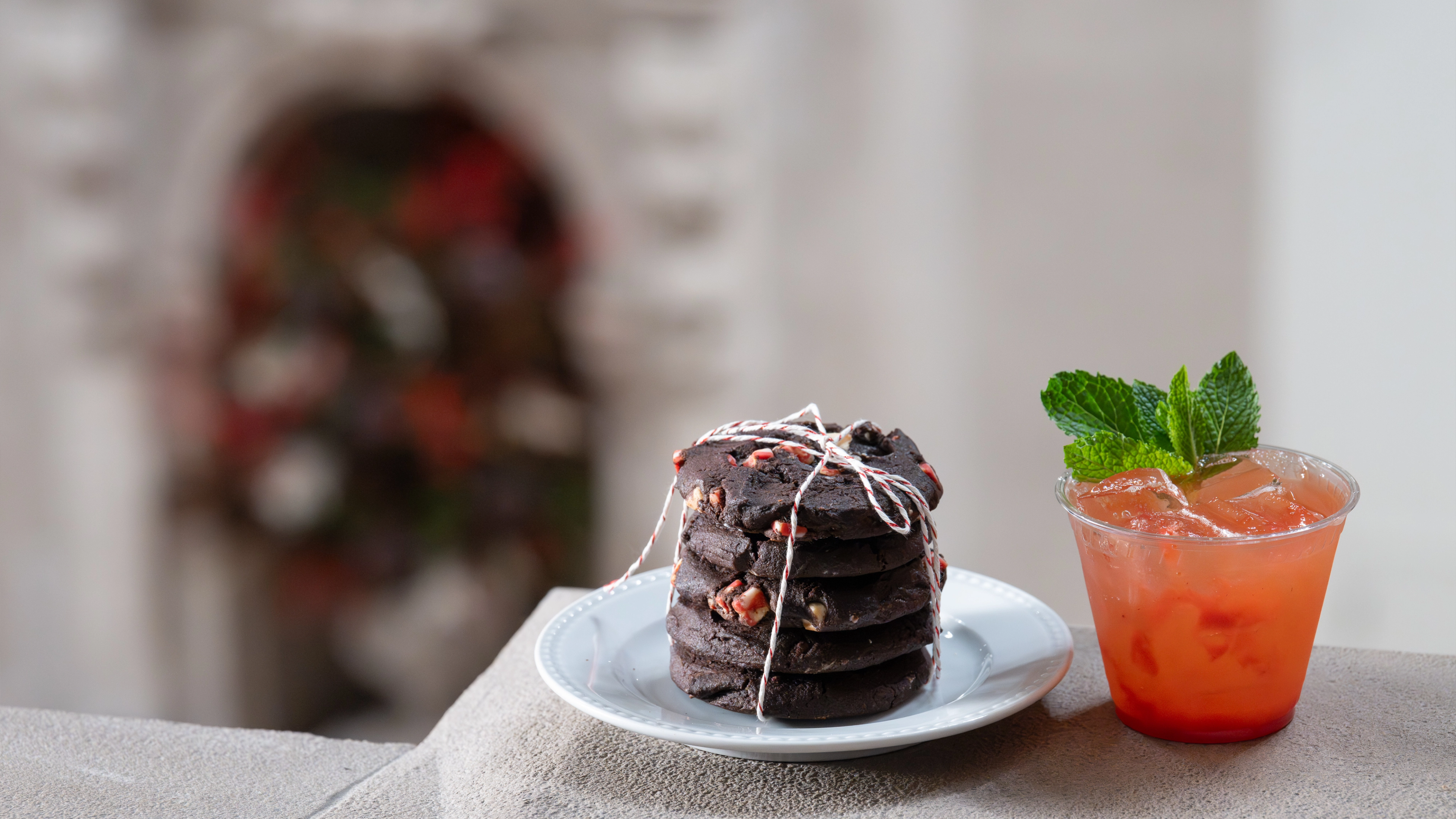 A stack of holiday cookies wrapped in ribbon next to a cocktail. 