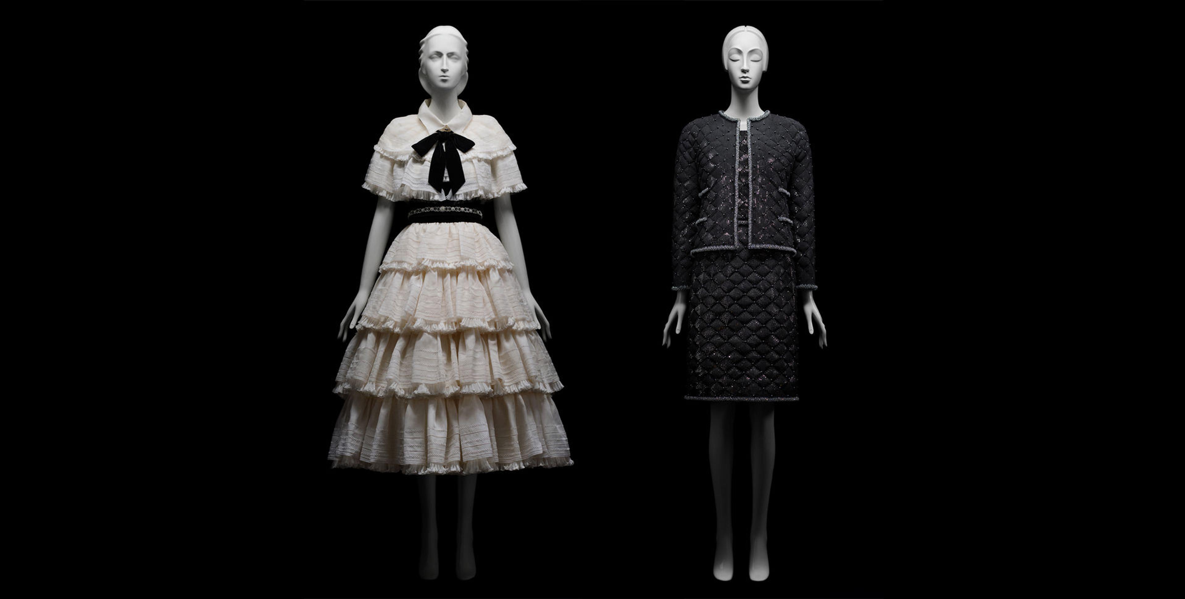 Two Mannequins behind a black background wearing a white dress on the right and a black on the left designed by Karl Lagerfeld.