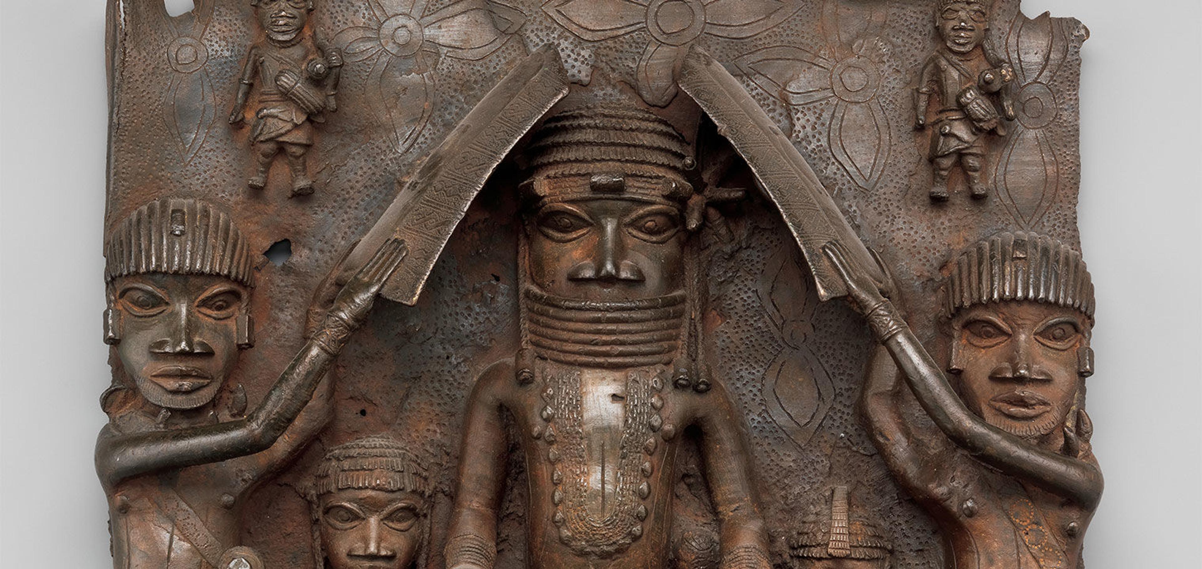 Detail of a sculptural relief plaque made of brass depicting a central figure on horseback flanked by smaller attending figures to either side.