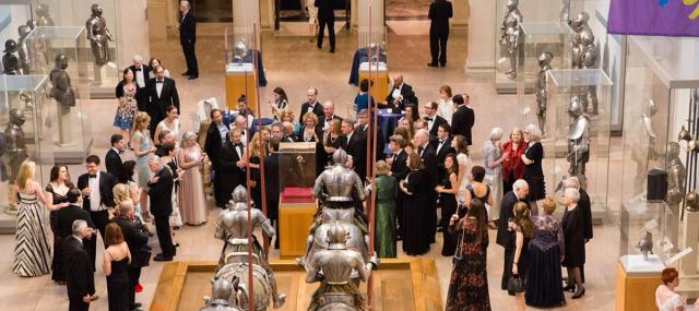 Patrons in formal wear socializing in the Arms and Armor galleries.