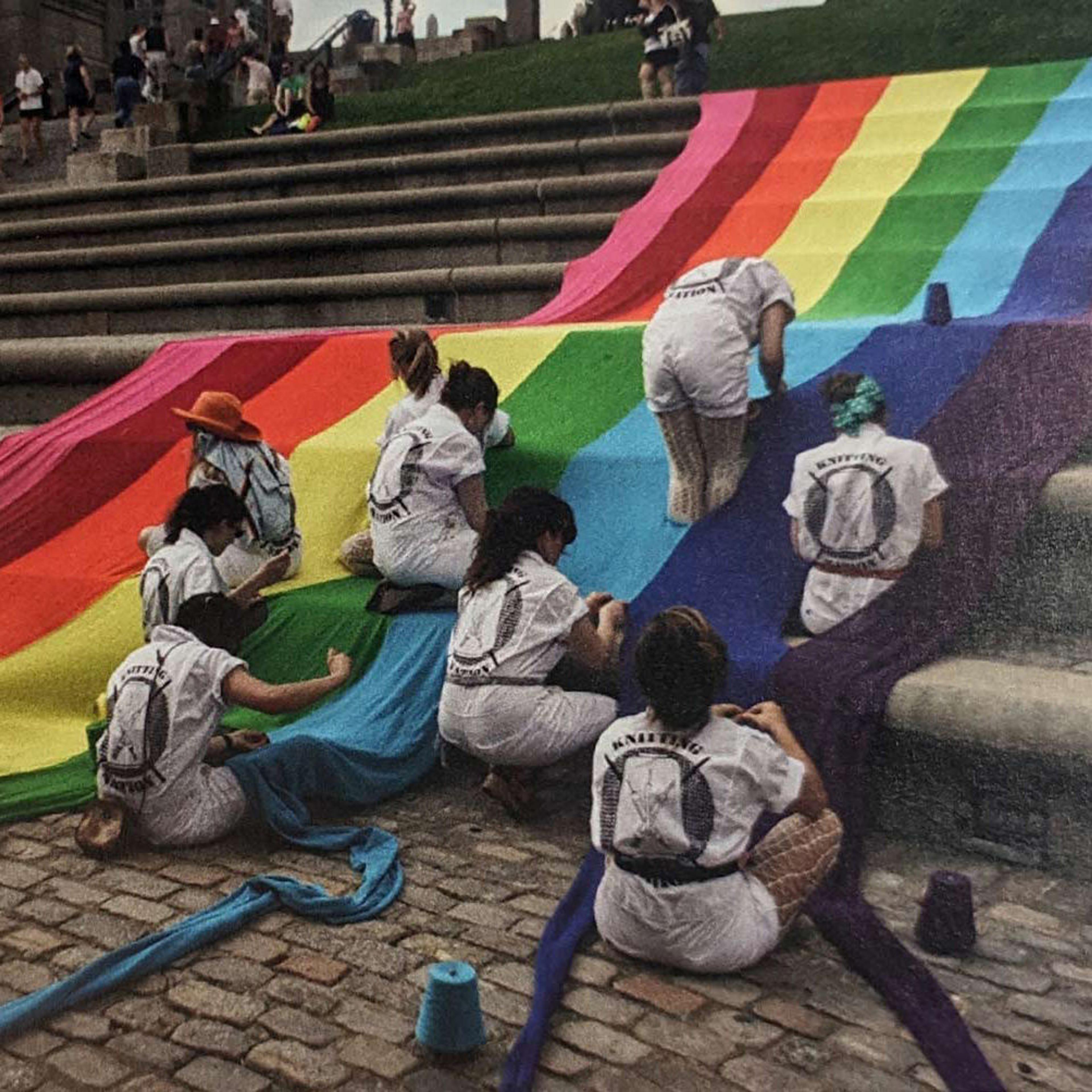 Pride flag being draped over a large public staircase
