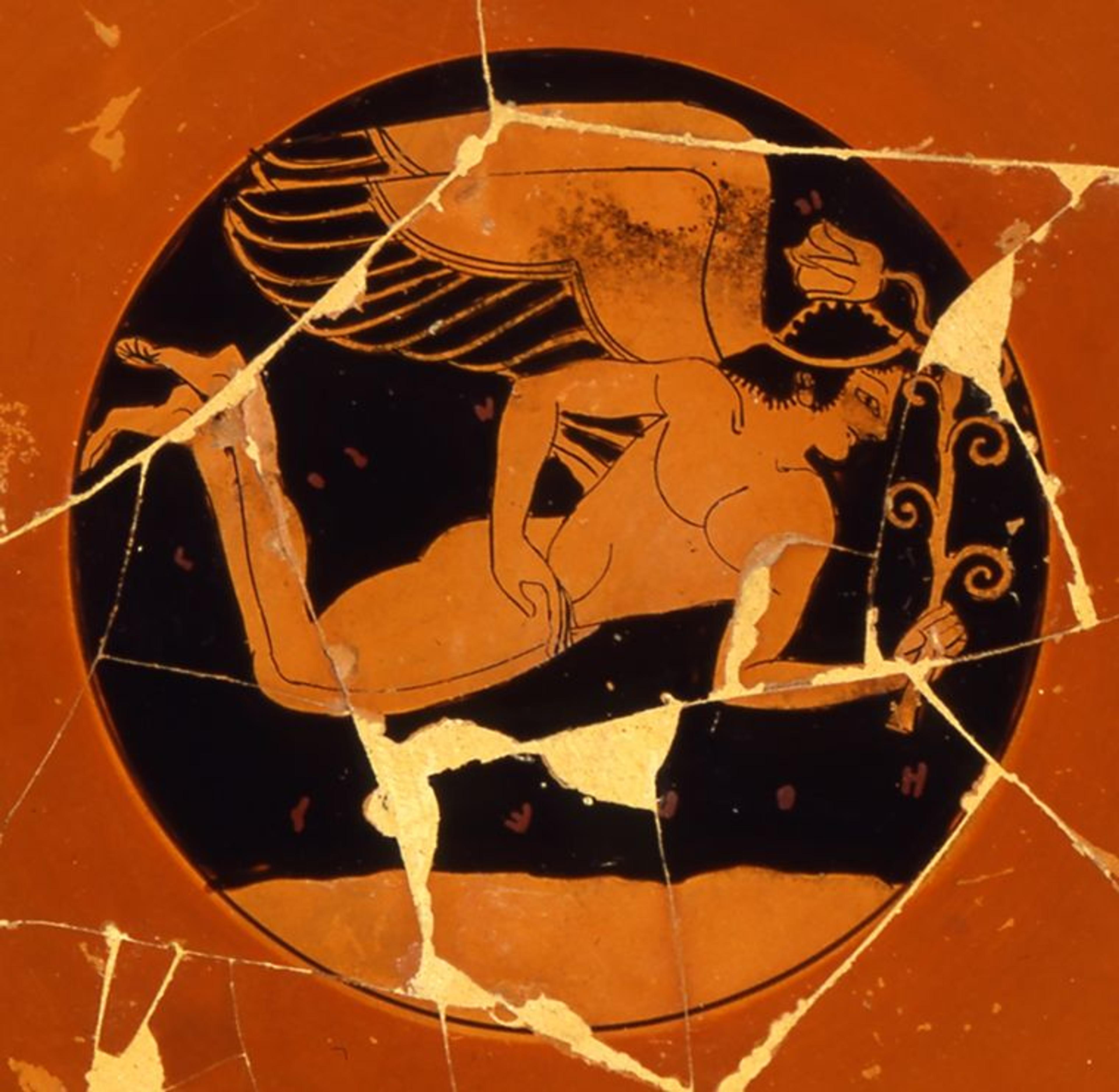 Interior of a red Greek drinking cup with a painting of a winged figure in flight holding a flower