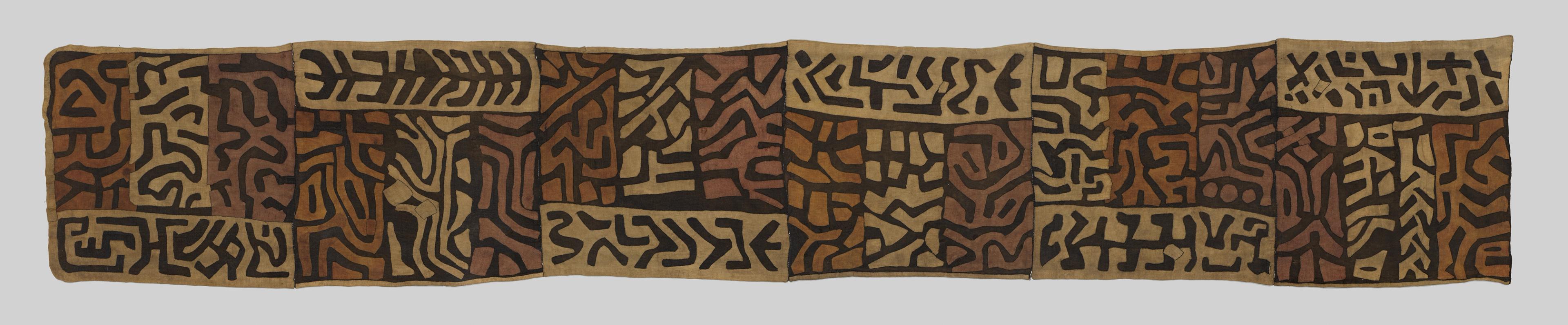 Wrap skirt with black geometric symbols arranged in sections across a brown and tan woven surface.