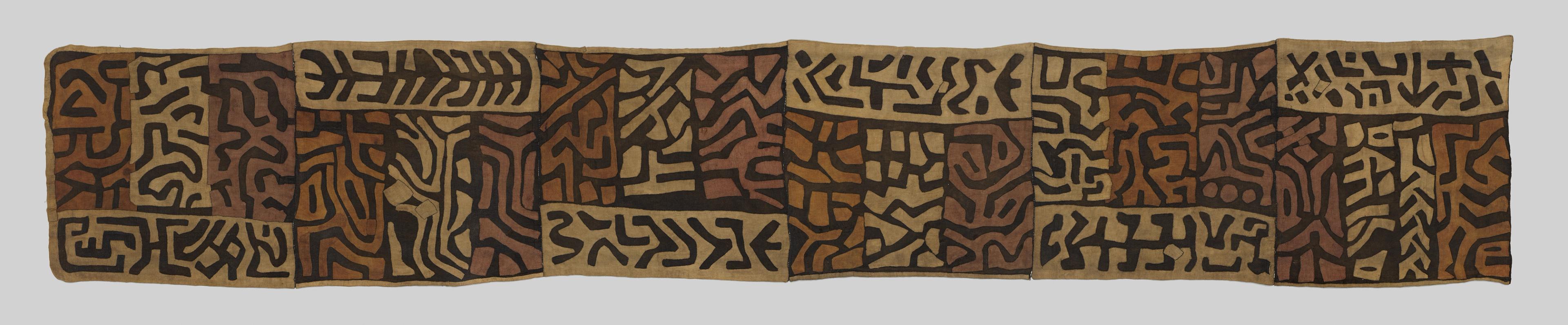 Wrap skirt with black geometric symbols arranged in sections across a brown and tan woven surface.